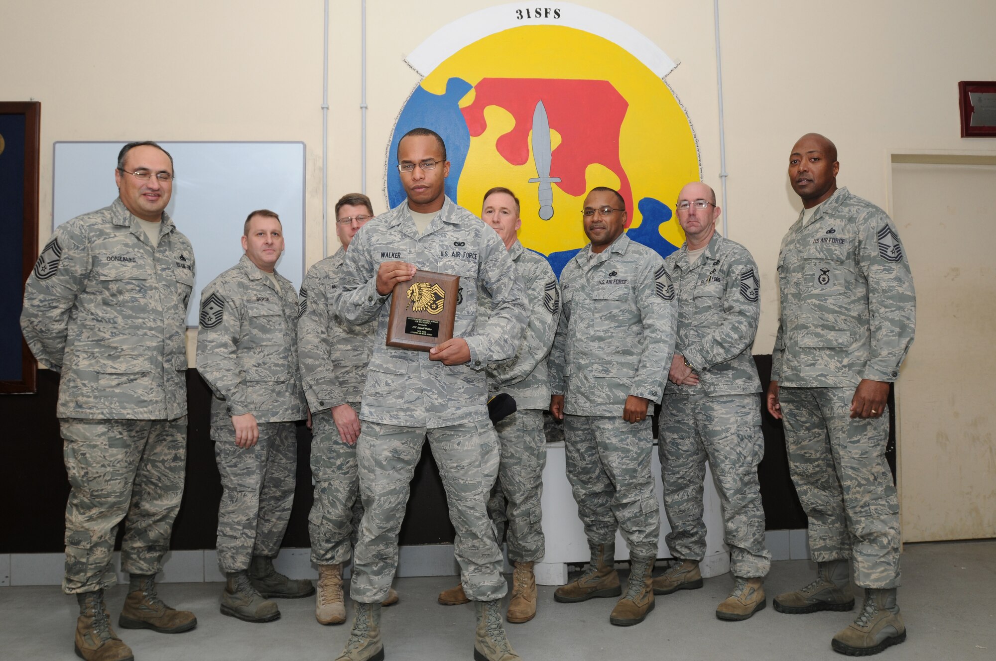 Airman 1st Class Jaquell Walker, 31st Security Forces Squadron, receives the Aviano Chief's Choice Award for November 2009 from Chief Master Sgt. Mike Cote, 31st Mission Support Group chief enlisted manager, (center right) along with fellow Aviano chiefs. (U.S. Air Force photo/Airman LaVel Sterling)