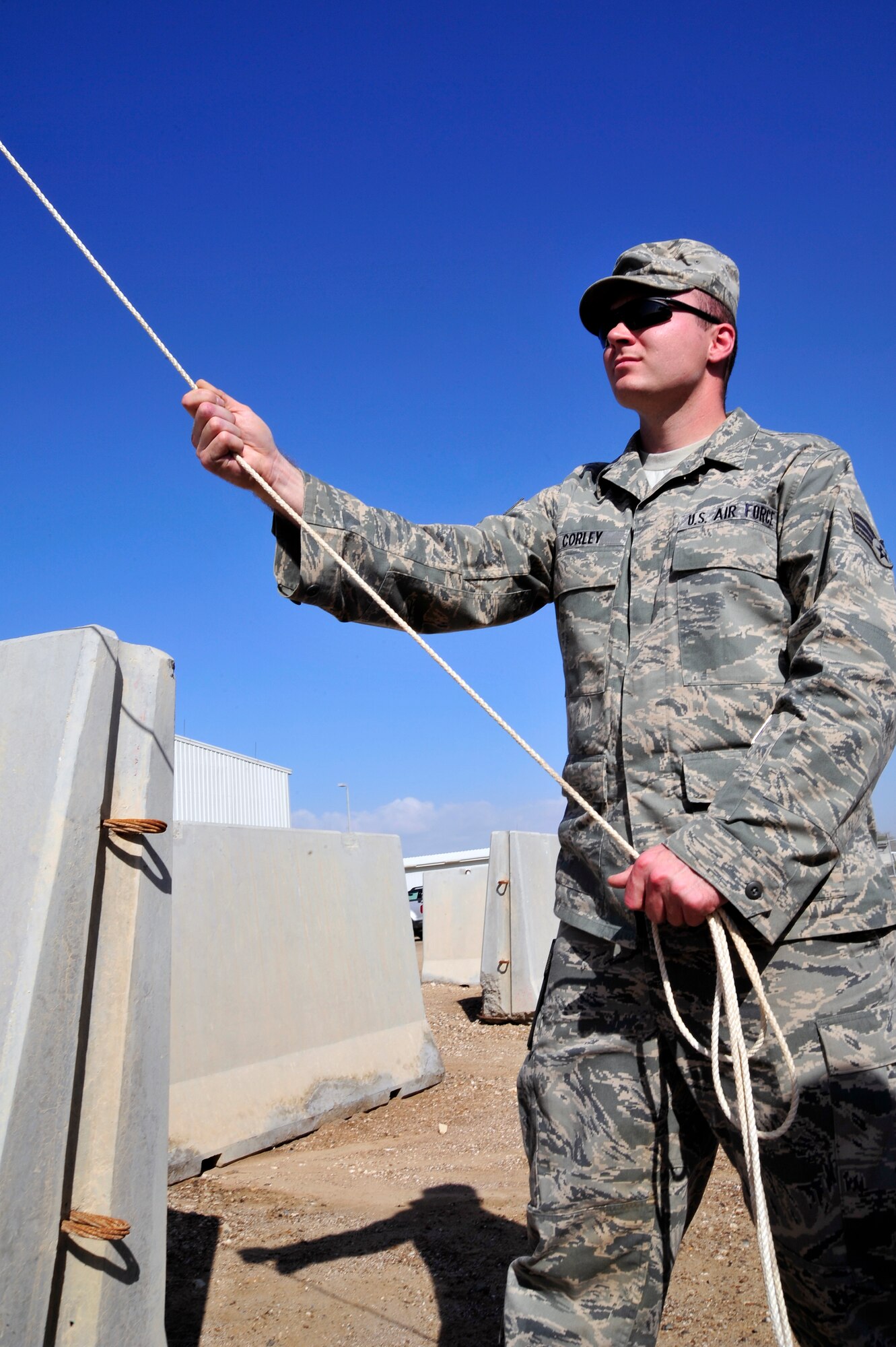 SOUTHWEST ASIA - Senior Airman Cody Corley, 380th Expeditionary Communications Squadron uses rope to make minor adjustments as a crane moves a satellite dish into position Dec. 21, 2009. Airman Corley is deployed from Buckley Air Force Base, Colo., and grew up in Nashville, Tenn. (U.S. Air Force photo/Tech. Sgt. Charles Larkin Sr)