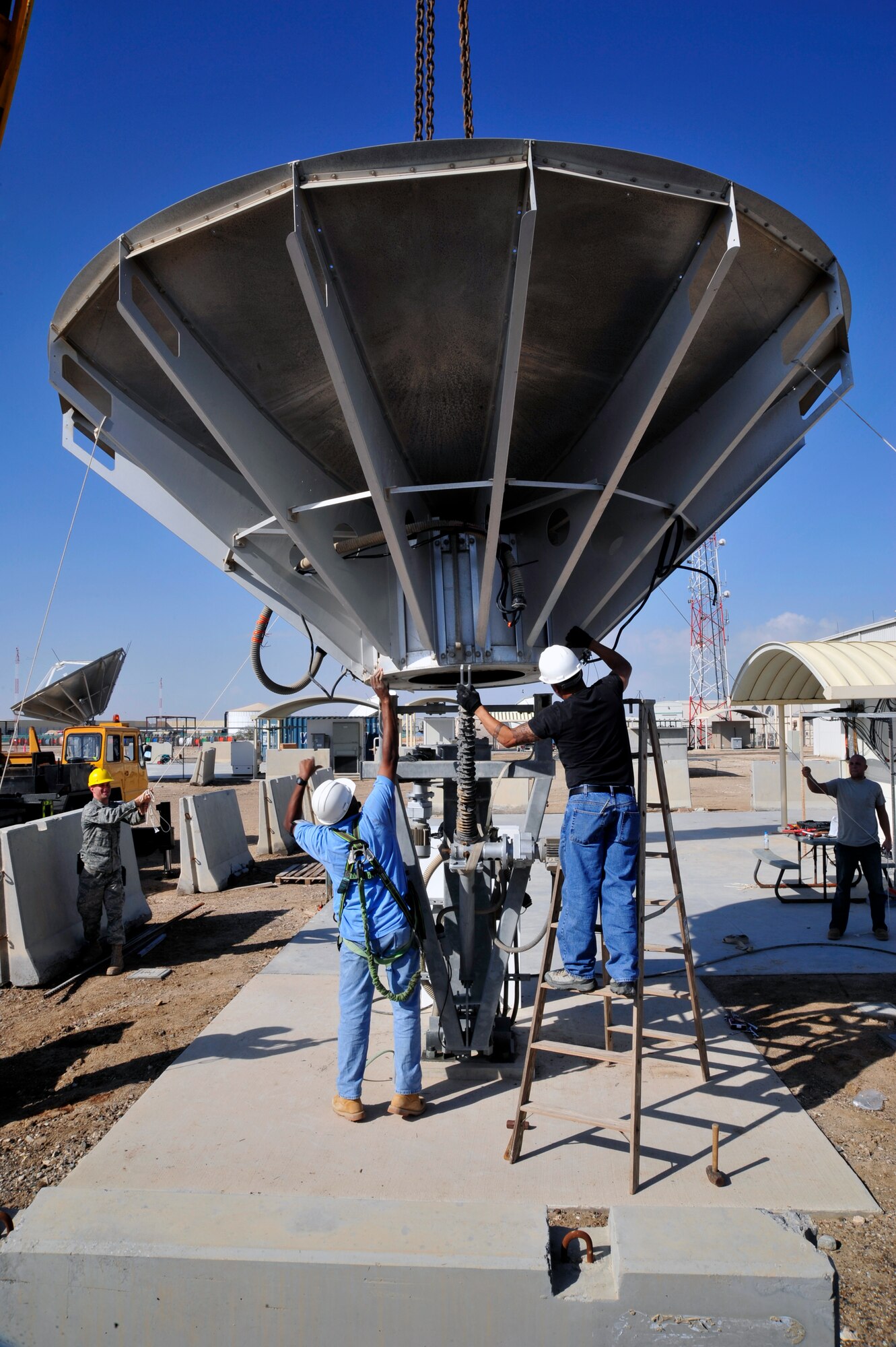 SOUTHWEST ASIA—Airmen and contractors from the 380th Expeditionary Communications Squadron make final adjustments to a satellite dish before it was secured to a pedestal Dec. 21, 2009. The satellite dish was removed and reattached to allow the 380th ECS to rotate a pedestal, to increase satellite signal reception. (U.S. Air Force photo/Tech. Sgt. Charles Larkin Sr)