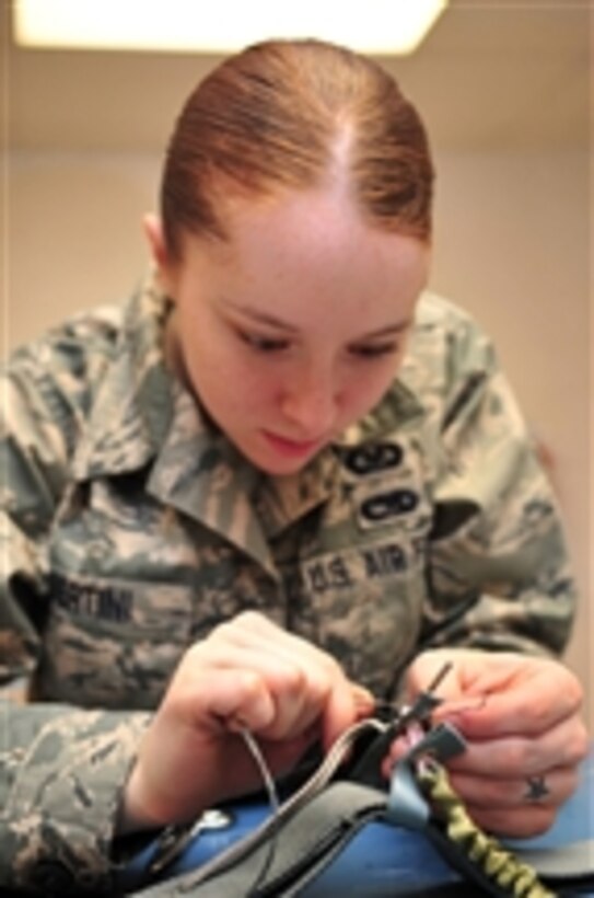 U.S. Air Force Airman 1st Class Emily Bertini, a life support journeyman with the 4th Operations Support Squadron, replaces tackings on a parachute’s riser at Seymour Johnson Air Force Base, N.C., on Dec. 15, 2009.  Tackings keep parachute rigging parts in place so they do not come apart.  