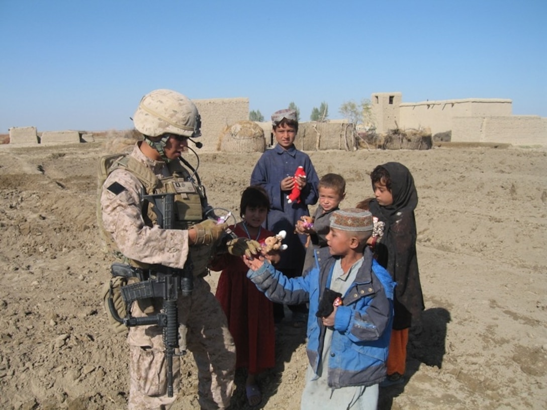 Capt. Tin Nguyen, a reserve infantry officer with 4th Light Armored Reconnaissance Battalion, gives toys and candy to local children during a December, 2009 patrol to meet with local elders in a rural village here.  The battalion’s reserve officers are currently leading several hundred Marines in counterinsurgency operations during their seven-month deployment to Afghanistan.