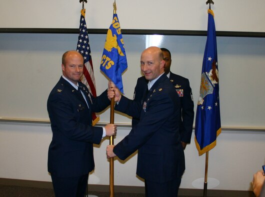 KIRTLAND AIR FORCE BASE -- Col. William Reese, left, commander of the 505th Distributed Warfare Group, presents the 705th Combat Training Squadron guidon to new commander Lt. Col. Dan Pepper during the squadron change of command ceremony Dec. 21. The squadron, which facilitates the Distributed Mission Operations Center, reports to the 505th Command and Control Wing at Hurlburt Field, Fla. (U.S. Air Force photo)