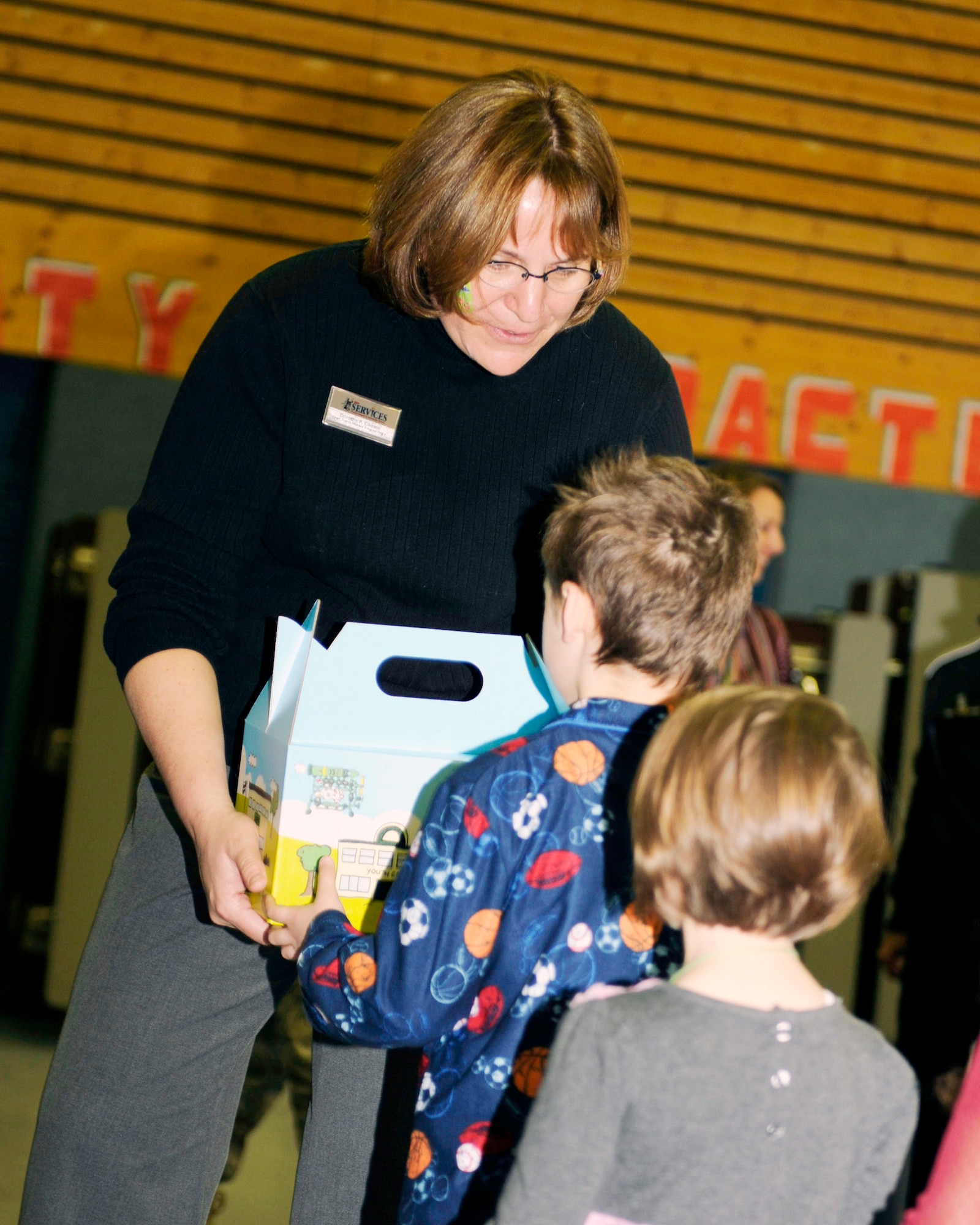 Dorothy Choate hands out Cuzzie Cares Deployment Kits at Ramstein Elementary School Dec. 17, 2009, at Ramstein Air Base, Germany. Cuzzie, designed by Trevor Romain, is an inventive bear that creates flying machines with the help of his ground crew and is the centerpiece of a new kit designed to comfort school-age children during deployments. Ms. Choate is the 86th Services Squadron family member program flight chief. (U.S. Air Force photo/Airman 1st Class Brea Miller)