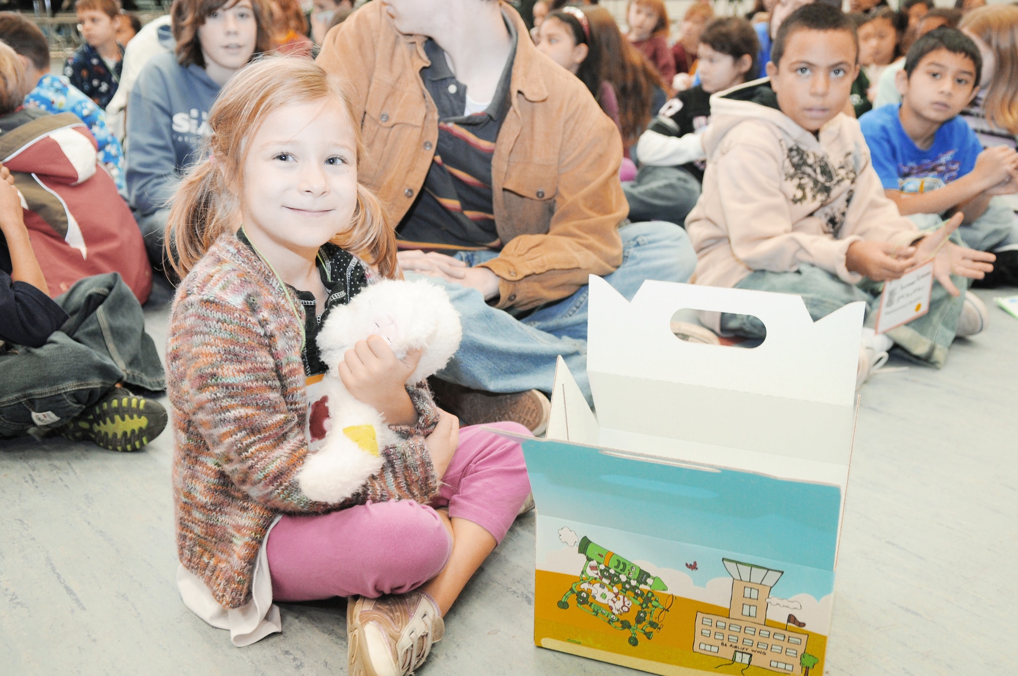 Natalie Zenk, 6, smiles after receiving one of the first Cuzzie Cares Deployment Kits Dec. 17, 2009, at Ramstein Air Base, Germany. These kits, designed to comfort school-age children during their parent's deployment, contain journals, stationary, photo albums, countdown calendars, post cards, playing cards, dog tags and a special friend, Cuzzie the Bear. Natalie is the daughter of Capt. Micheal Zenk from the 86th Aeromedical Evacuation Squadron. (U.S. Air Force photo/Airman 1st Class Brittany Perry)