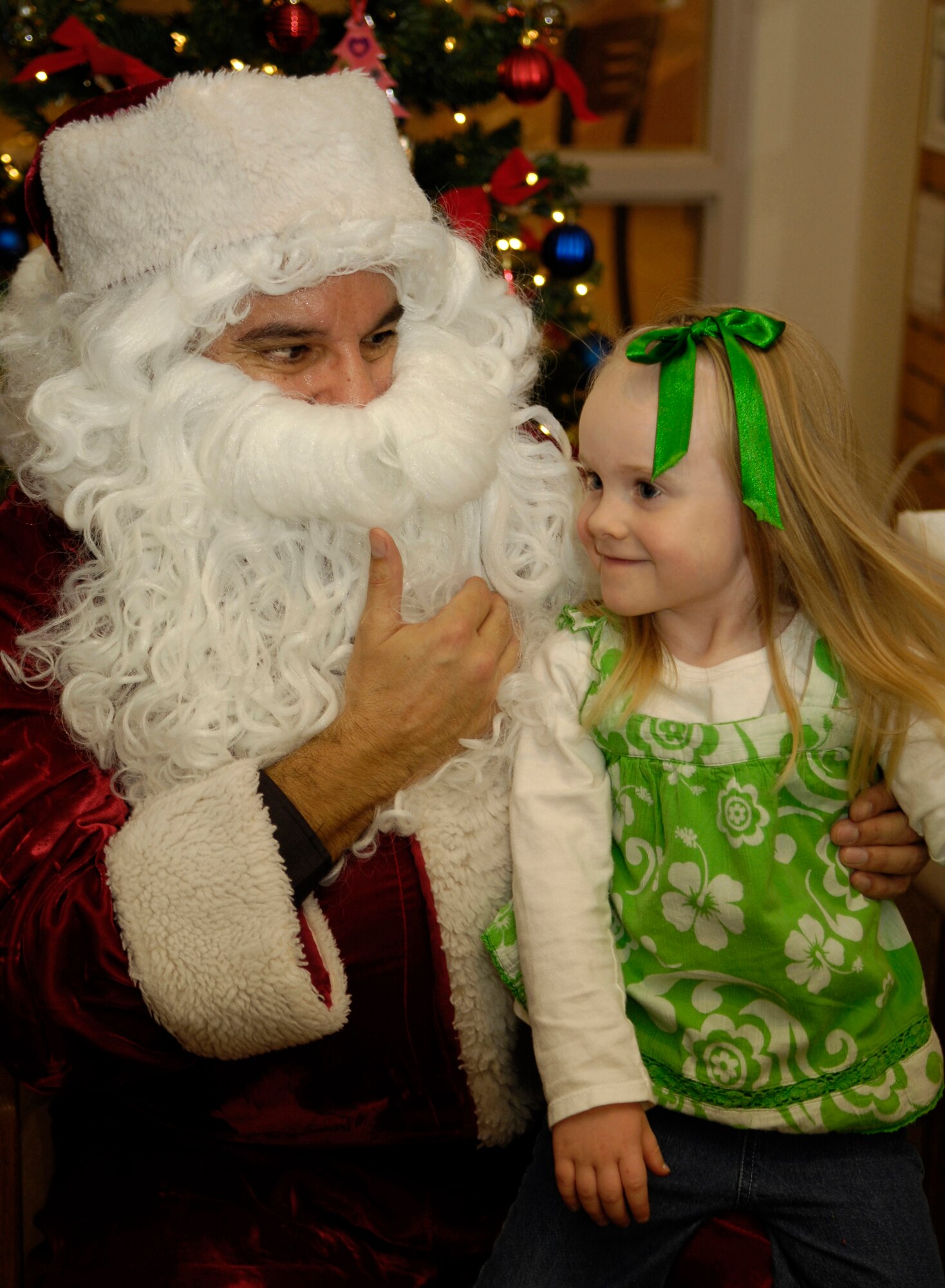 HOLLOMAN AIR FORCE BASE, N.M. -- Ella Robinson, 4, daughter of Capt. Brett Robinson, 49th Fighter Wing Legal Office, chats with Santa after hearing him read a story to children visiting at Ahren's Memorial Library, Dec. 16. Santa posed for pictures with all of the boys and girls who were there. More than thirty children came to the library to hear Santa read them a Christmas story. (U.S. Air Force photo by Tom Fuller)