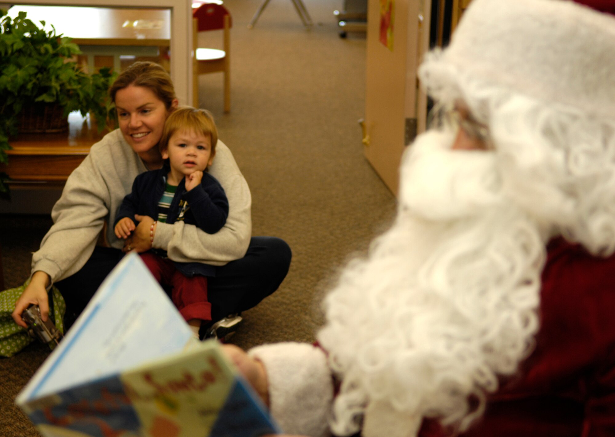 HOLLOMAN AIR FORCE BASE, N.M. -- Mayne Porter, 2, son of Maj. Maynard Porter, 846th Test Squadron, listens intently to Santa with his mother, Lindsay Porter, Dec. 16 at Ahren's Memorial Library. More than thirty children came to the library to hear Santa read them a Christmas story. (U.S. Air Force photo by Tom Fuller)