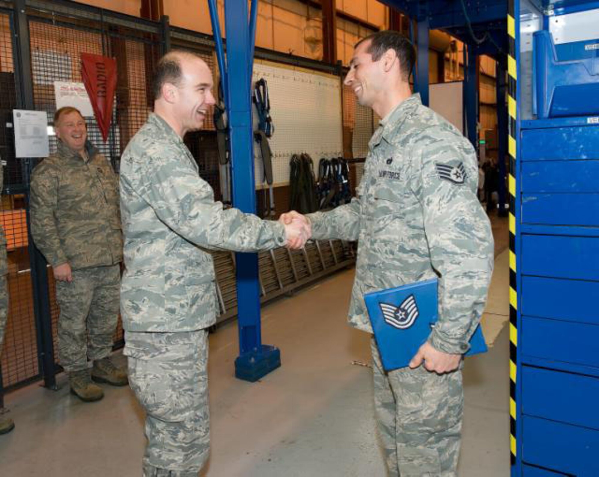 Col. Manson Morris, 436th Airlift Wing Commander, congratulates Staff Sgt. Jared Flores, 436th Aerial Maintenance Squadron hydraulic craftsman on his STEP promotion to Tech. Sgt after handing him the promotion binder. A STEP promotion is given by the wing commander to an outstanding worker who has been nominated and presented by their supervisor.