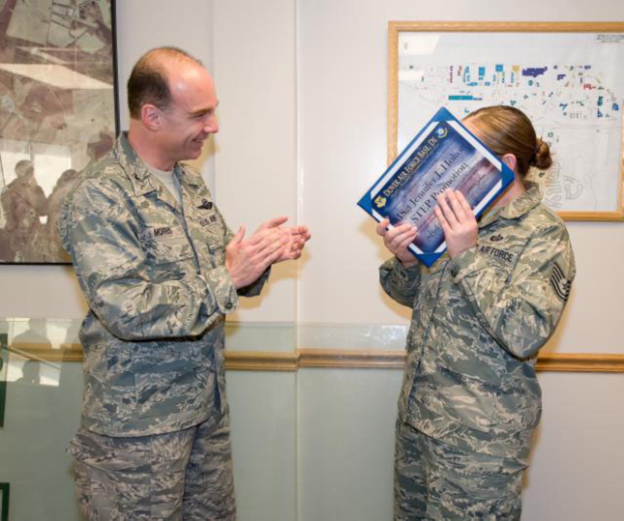 Col. Manson Morris, 436th Airlift Wing commander, applauds Tech. Sgt. Jennifer Holton, 436th Force Support Squadron non-commissioned officer in charge of first time airman course, on her STEP promotion to Master Sgt. after handing her the STEP promotion binder. 