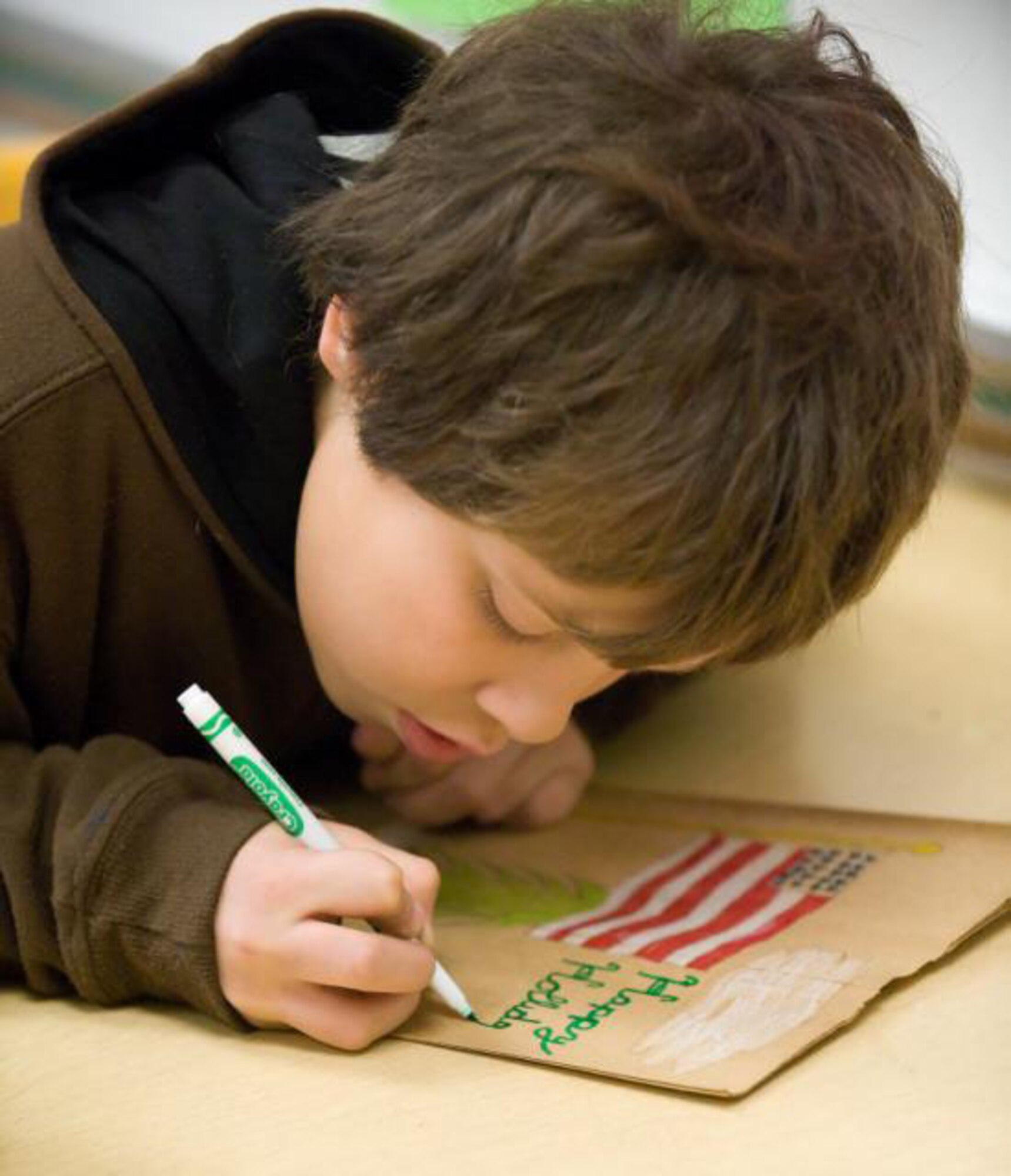 Jeremy Birch, a fourth grade student at Welch Elementary focuses on writing a message of 'Happy Holidays' on a paper bag. The fourth grade class at Welch Elementary works together with USO Delaware by decorating paper bags that will be filled with goodies and handed out at Operation Cookie Drop and to servicemembers deploying this holiday season. (US Air Force photo / Jason Minto)
