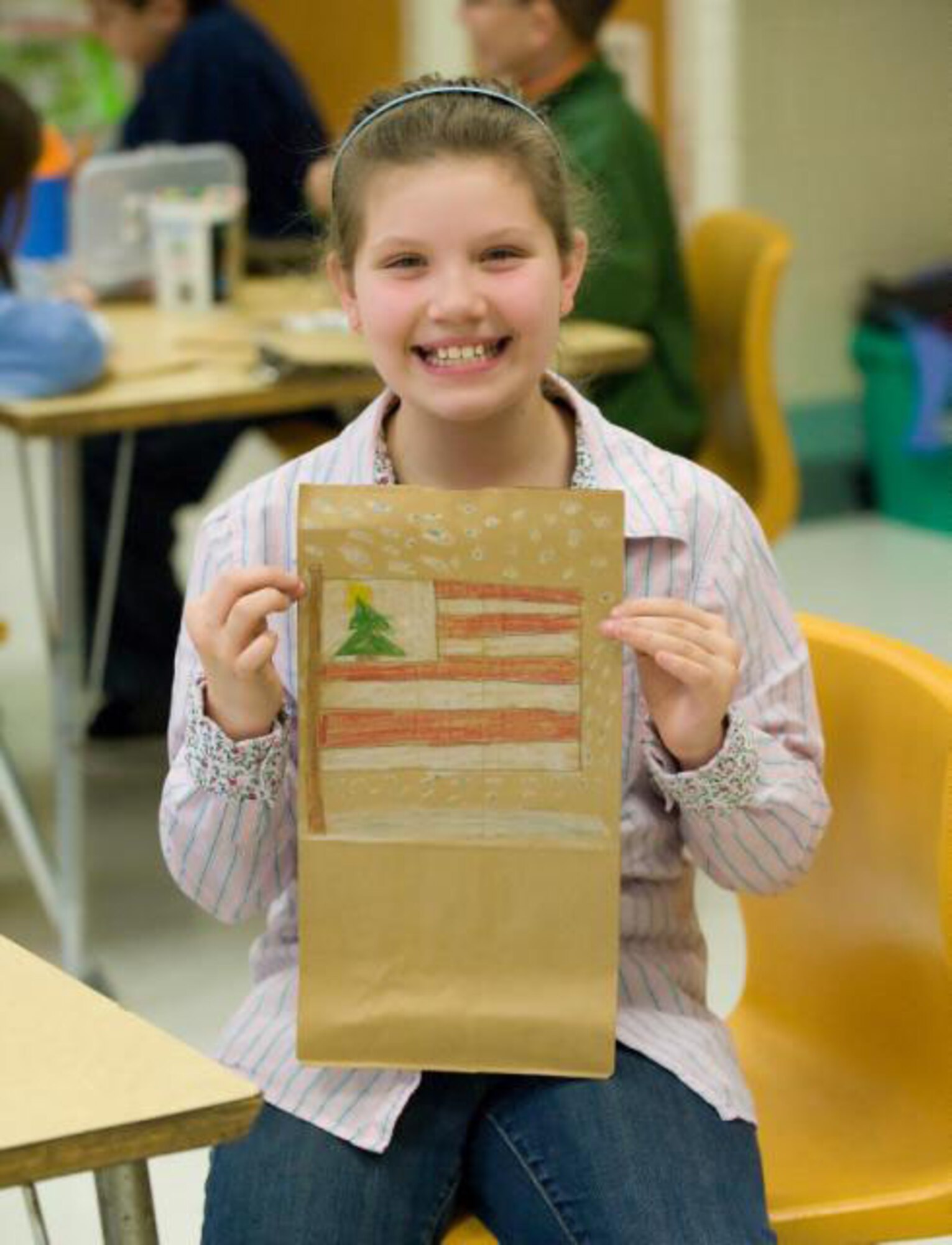 Kaylie Weber, a fourth grade student at Welch Elementary proudly displays her art work on this paper bag that will be handed out at Operation Cookie Drop and to servicemembers deploying this holiday season, coordinated through the USO Delaware. The fourth grade class at Welch Elementary is working together with the USO to spread holiday cheer to those who pass through the Dover Passenger Terminal by handing out hand-decorated bags with goodies in them. (US Air Force photo / Jason Minto)