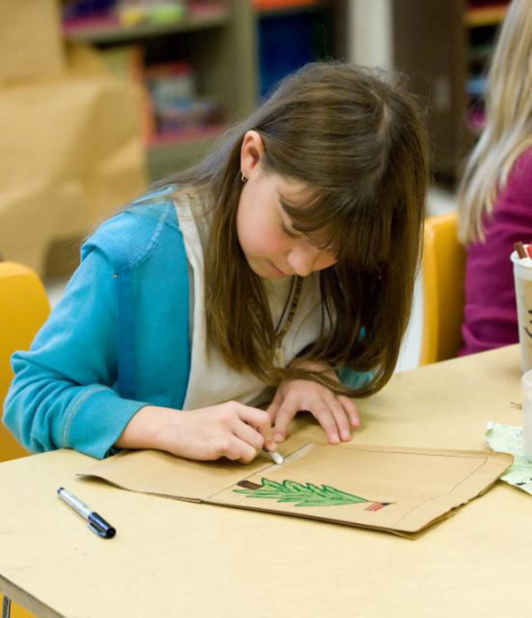 Abigail Davison, a fourth grade student at Welch Elementary works hard on her drawing of a holiday tree. The fourth grade class at Welch Elementary decorates paper bages to be filled with goodies and handed out at Operation Cookie Drop and to servicemembers deploying this holiday season. This project was coordinated with the USO Delaware. (US Air Force photo / Jason Minto)