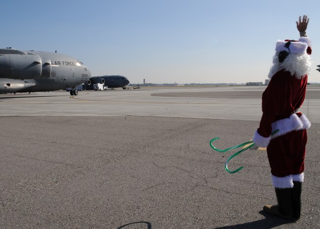 Maj. Aaron Sasson waves to the aircrew of a Charleston AFB C-17 on the flightline here Dec. 22 after marshalling the aircraft into a parking spot. The 437th Aircraft Maintenance Squadron voted for Major Sasson to dress up as Santa Claus while marshaling the C-17 for a booster club fundraiser which raised $800. Major Sasson is the operations officer for the 437 AMXS. (U.S. Air Force photo/Senior Airman Katie Gieratz)(RELEASED)