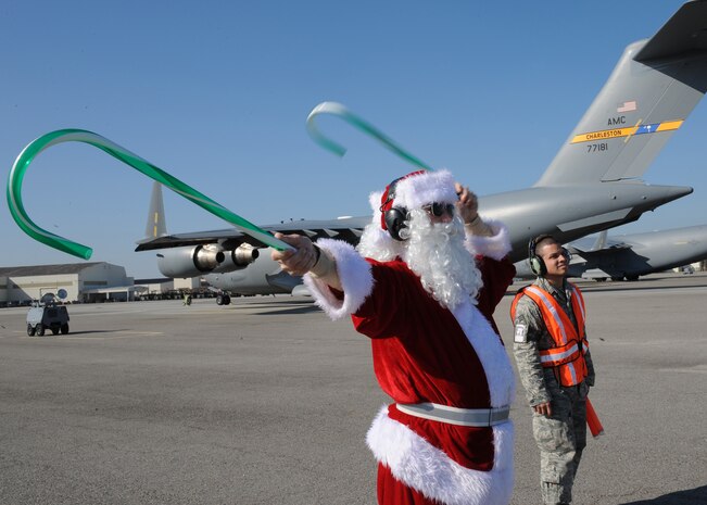 Maj. Aaron Sasson marshals in a Charleston AFB C-17 with a pair of oversized candy canes on the flightline here Dec. 22. The 437th Aircraft Maintenance Squadron voted for Major Sasson to dress up as Santa Claus while marshalling an aircraft for a booster club fundraiser which raised $800. Major Sasson is the 437 AMXS operations officer. (U.S. Air Force photo/Senior Airman Katie Gieratz)(RELEASED)