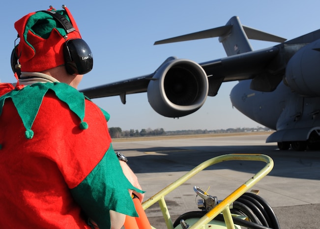 Chief Master Sgt. Derrell Wells performs a fire guard as an elf on the Charleston AFB flightline Dec. 22. The 437th Aircraft Maintenance Squadron booster club held a fundraiser which allowed individuals to vote on who they wanted to dress up as Santa Claus, an elf and a reindeer while marshalling in a C-17. Chief Wells is the 437 AMXS superintendent. (U.S. Air Force photo/Senior Airman Katie Gieratz)(RELEASED)