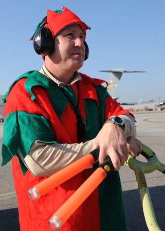 Chief Master Sgt. Derrell Wells performs a fire guard as an elf on the Charleston AFB flightline Dec. 22. The 437th Aircraft Maintenance Squadron booster club held a fundraiser which allowed individuals to vote on who they wanted to dress up as Santa Claus, an elf and a reindeer while marshalling in a C-17. Chief Wells is the 437 AMXS superintendent. (U.S. Air Force photo/Senior Airman Katie Gieratz)(RELEASED)