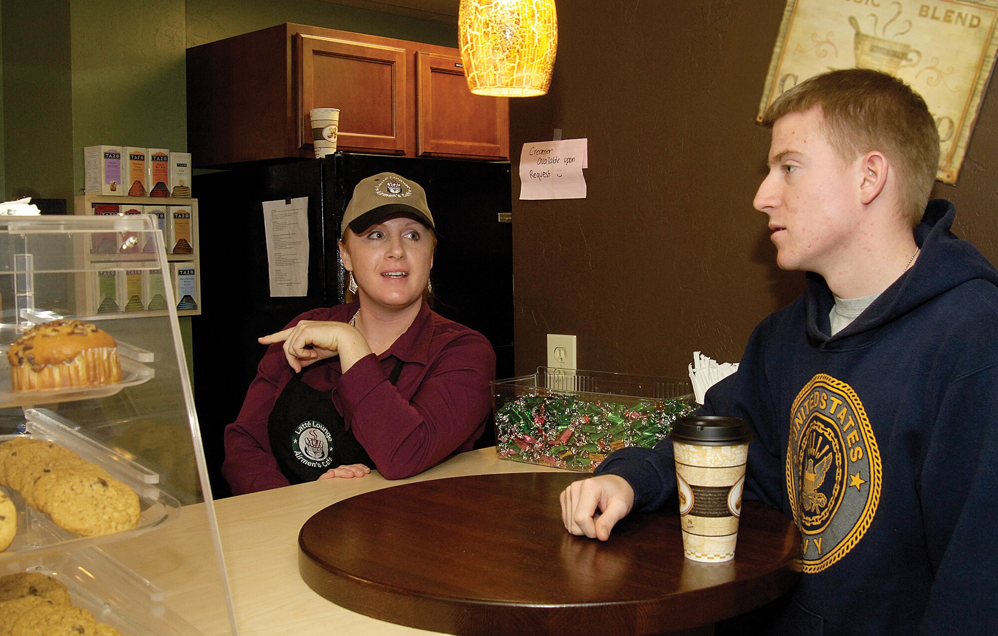 On a cold Friday night, Navy Fleet Reconnaissance THREE Airman Michael Wilson gets a free coffee and a warm, friendly greeting by volunteer Staff Sgt. Lisa Vincelette at the chapel-sponsored Latté Lounge. Located in Loop Hall, Bldg. 5913, the lounge offers Airmen a positive, upscale place to play billiards or electronic games, meet friends and get free café-type refreshments. Sergeant Vincelette is an IMA and chaplain assistant who also donates many hours at the Lounge. She says being a part of such an outreach is exciting. “It charges me,” she says. “You know, they say it’s more blessed to give than receive.” (Air Force photo by Margo Wright)

