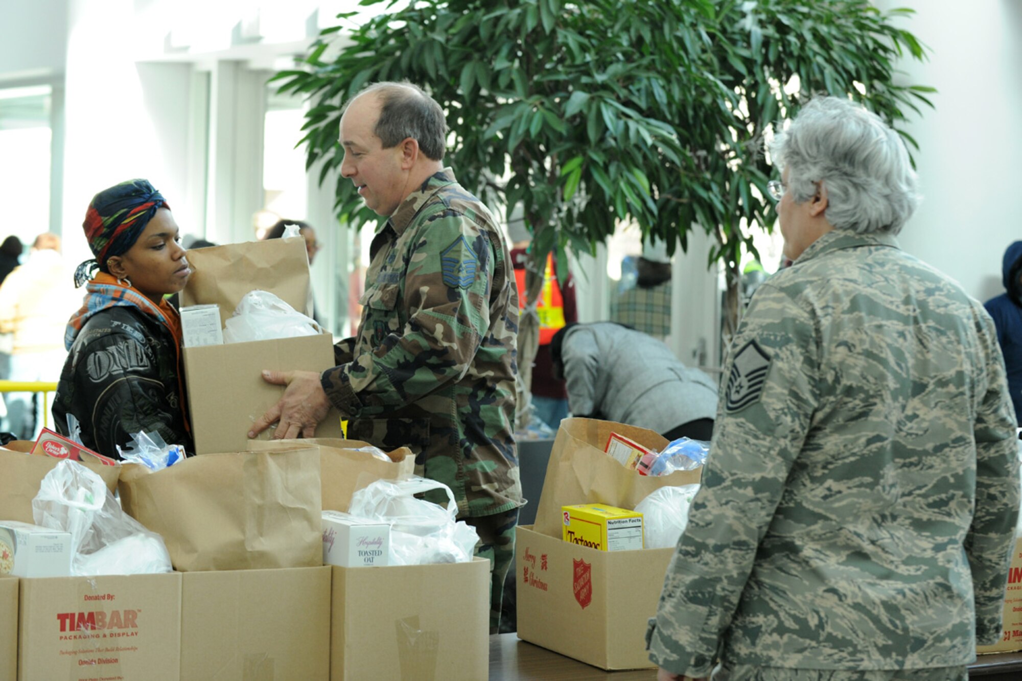 US Air Force Master Sgt. Michael G. Kondra and US Air Force Master Sgt. Donna M. Giambalvo present a Syracuse NY resident with food for her Holiday meal at the Oncenter Complex in Syracuse, NY on 22 Dec. 2009. Kondra and Giambalvo were volunteering at the Annual Christmas Bureau Salvation Army Food and Gift drive supplying needy families with gifts for their children and food for their Holiday meal. (US Air Force photo by Tech. Sgt. Jeremy M. Call/Released)