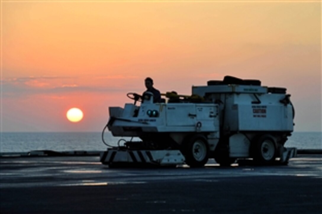U.S. Navy Seaman Michael Beckwith operates a flight deck scrubber during a deck wash aboard aircraft carrier USS Nimitz at sunset, Dec. 18, 2009, in the North Arabian Sea. The Nimitz Carrier Strike Group is on a routine deployment to the U.S. 5th Fleet area of operations.