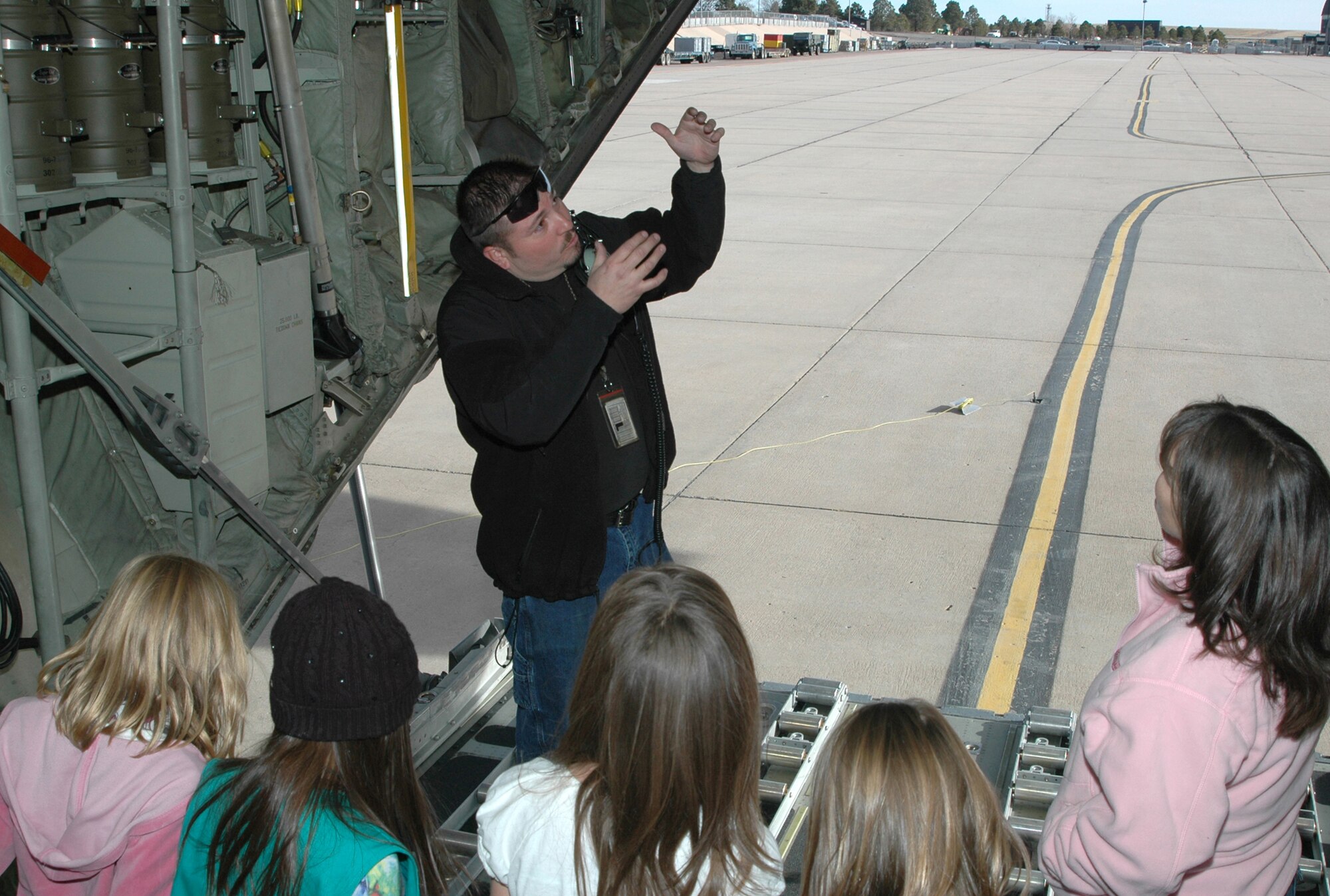 Manny Ortega, a C-130 aircraft crew chief assigned to the 302nd Maintenance Group, explains how cargo is delivered from the back of the aircraft in flight Dec. 21 to girls of Girl Scout Troop 225 at Peterson Air Force Base, Colo. The girls, from Woodland Park, Colo., visited the 302nd Airlift Wing where they learned about flying, the C-130 Hercules and the aerial firefighting mission of the wing. The visit allowed the girls to further earn their aeronautical badge. The 302nd Airlift Wing is located in southern Colorado. (U.S. Air Force photo/Staff Sgt. Stephen J. Collier)