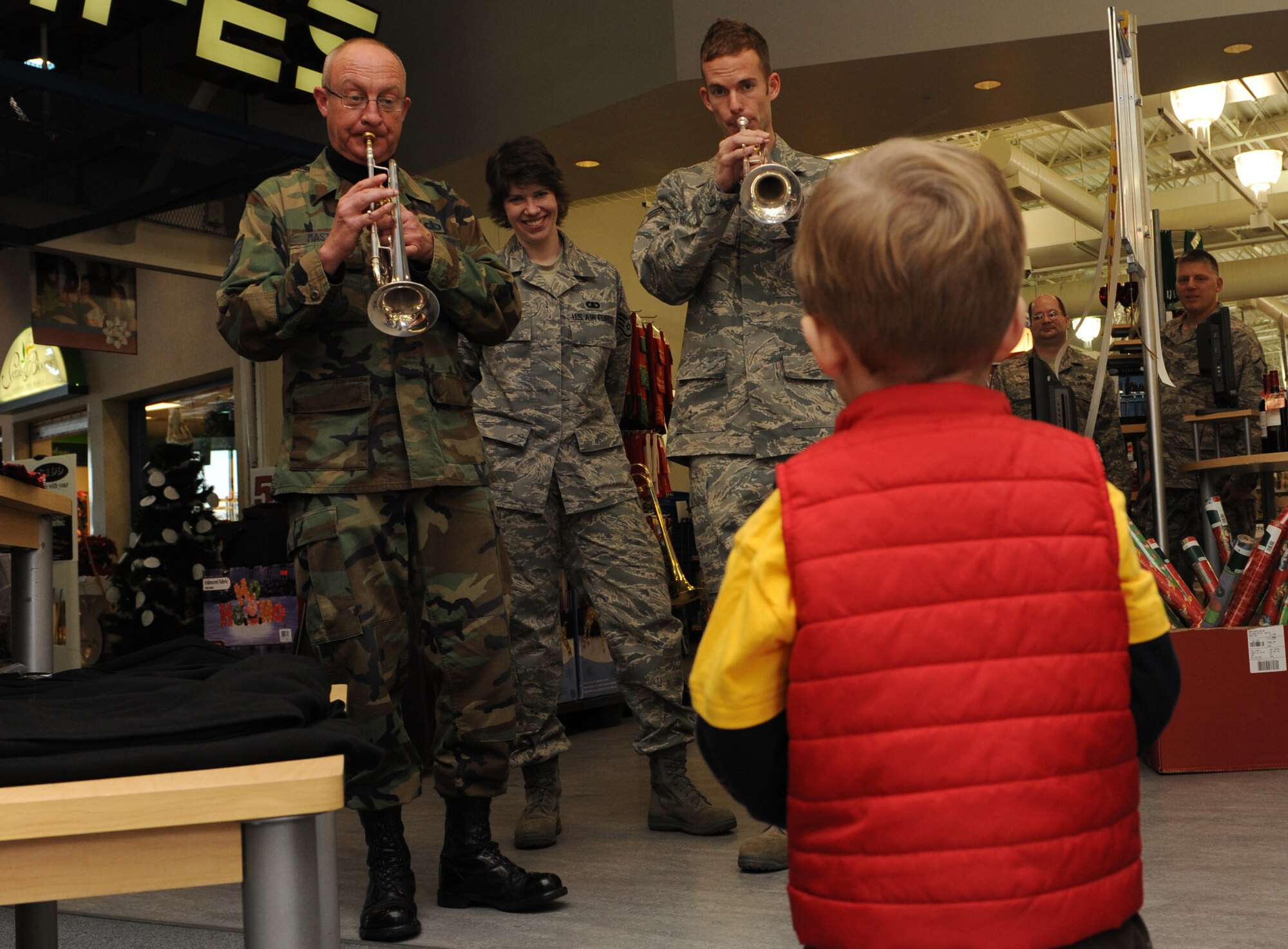 MOUNTAIN HOME AIR FORCE BASE, Idaho -- Ryder Arderton, 2 years old, listens as members from the Air Force Band of the Golden West brass ensemble play Christmas carols at the base exchange Dec. 17. The band had a two day visit and played at various locations on base spreading the Christmas joy to all. (U.S. Air Force photo by Airman 1st Class Deborah Lockhart)