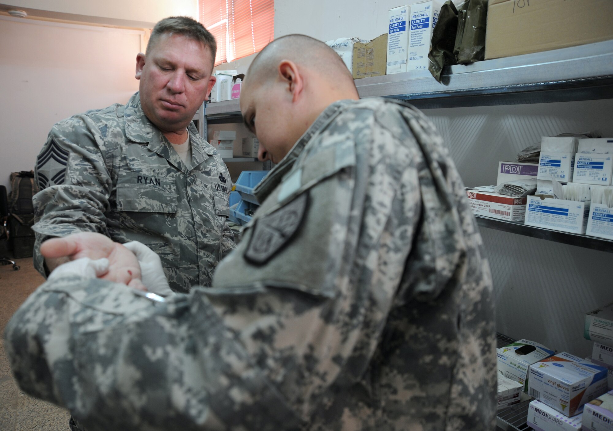 CAMP TAJI, Iraq -- Air Force Chief Master Sgt. Tim Ryan (left), security forces manager with the 732nd Expeditionary Security Forces Squadron Detachment 3, receives medical treatment from Army Spc. Tommy Turner, a combat medic attached to the 732nd ESFS Det. 3, Dec. 12, 2009. Specialist Turner recently saved an Airman's life after his vehicle was hit by an explosively formed projectile while out on a mission. Chief Ryan is deployed from Dyess Air Force Base, Texas, and hails from Oakfield, Wis. Specialist Turner is deployed from the 248th Area Support Medical Company, Georgia Army National Guard, and hails from Rome, Georgia. (U.S. Air Force photo/Master Sgt. Trish Bunting)
