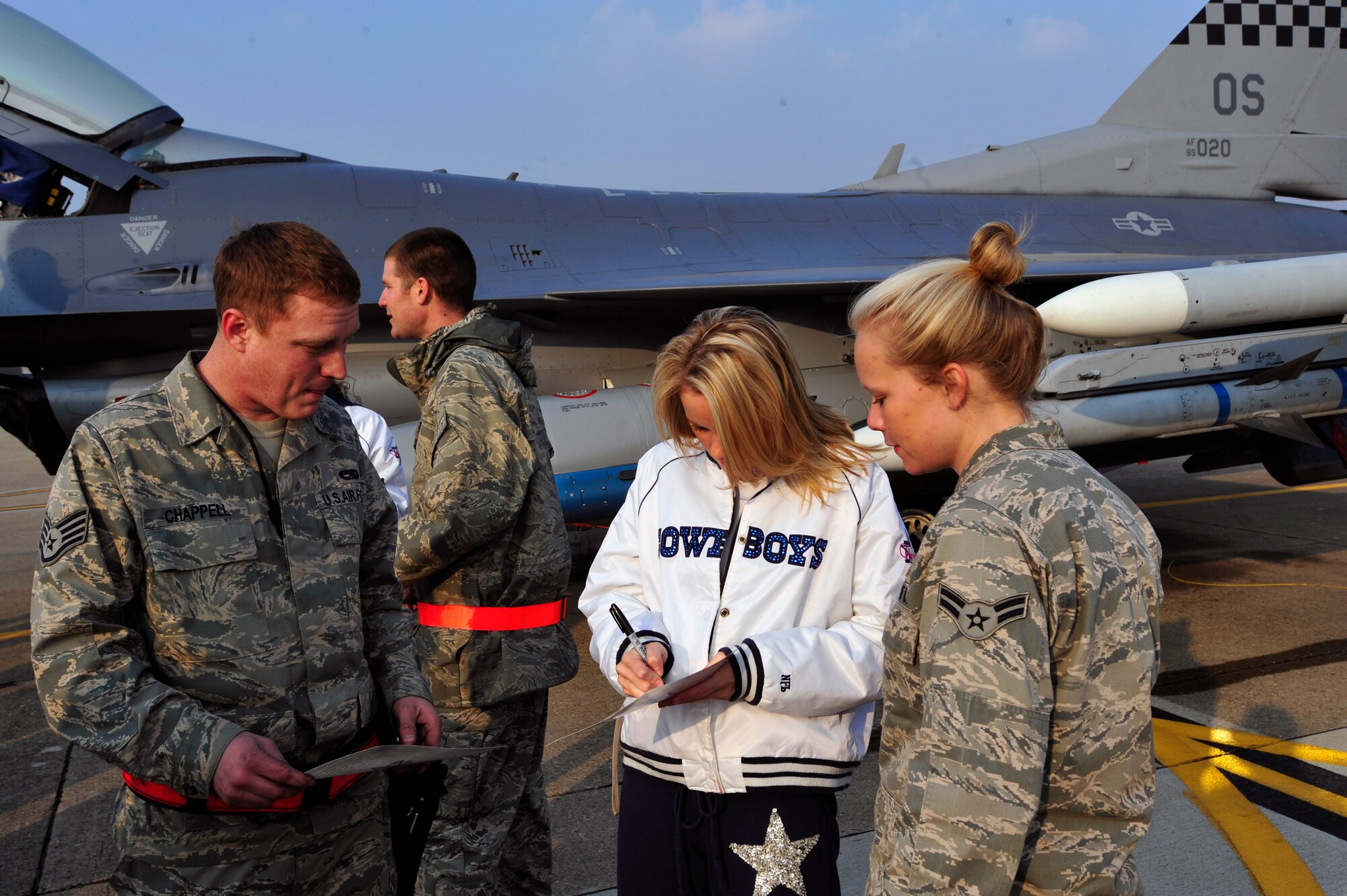 Whitney Isleib, Dallas Cowboys Cheerleader, signs autographs for Staff Sgt. Mark Chappell and Airman 1st Class Sarah Daniels, both 51st Aircraft Maintenance Squadron, Dec. 23. The cheerleaders came to Osan Air Base, Republic of Korea as part of their 69th USO Tour and performed at the Osan Base Theatre before moving on to Kunsan Air Base, ROK, for a Dec. 24 visit. (U.S. Air Force photo/1st Lt. Chris Hoyler)