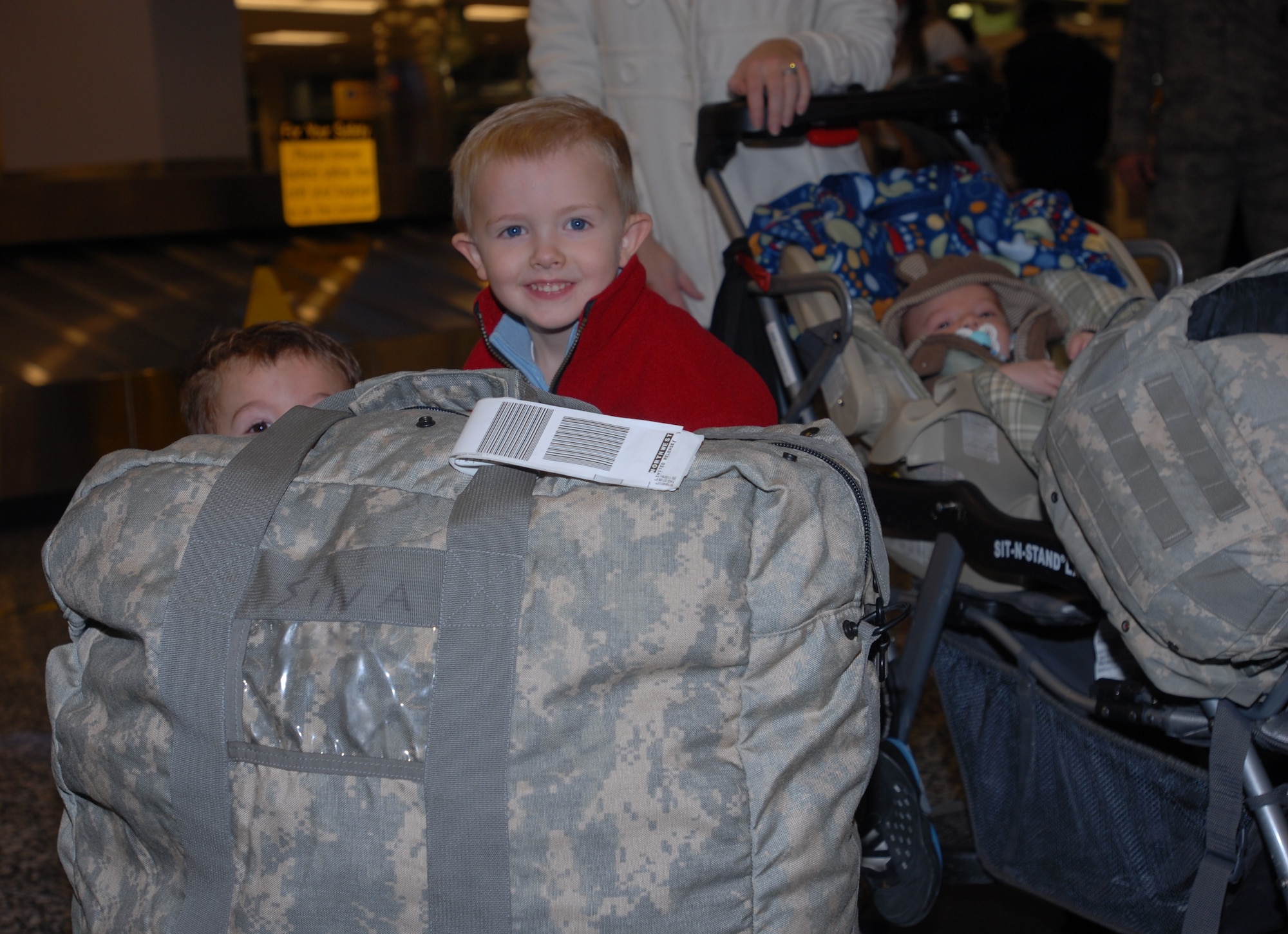 Connor and Dillan Silva, sons of Staff Sgt. Justin Silva, play a game of hide and go seek while waiting for Silva’s luggage at the Ted Stevens Anchorage International Airport Christmas Day. In the background is Silva’s two month old son, Caleb, who was born while he was deployed to Iraq. Silva is one of a dozen Airmen from the 3rd Security Forces Squadron that returned home from a six month deployment to Iraq.  (U.S. Air Force photo/Capt. Ashley Conner)
