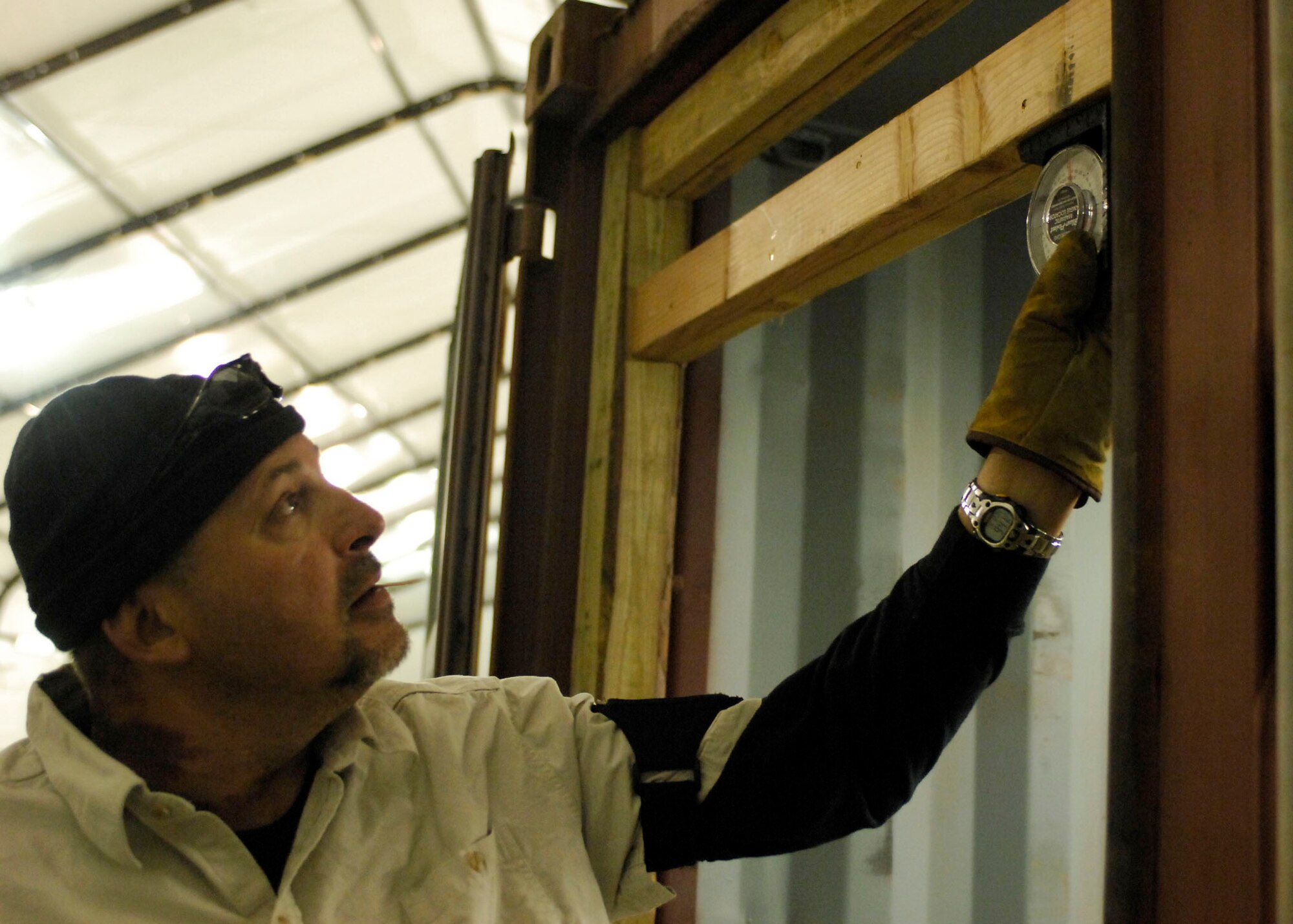 BAGRAM AIRFIELD, Afghanistan -- Richard Feece, a Henderson, Nev. native, assures the framing is level before continuing to build Dec. 27, 2009.  Mr. Feece is one of the team members sent to build the 4th Expeditionary Reconnaissance Squadron hanger before the personnel and aircraft arrive.  The Air Force MC-12s bring another capability to Operation Enduring Freedom because the MC-12 is not just an aircraft, but a complete collection, processing, analysis and dissemination system of Airmen committed to securing Afghanistan and protecting Afghan and Coalition lives.  (U.S. Air Force photo/Senior Airman Felicia Juenke)