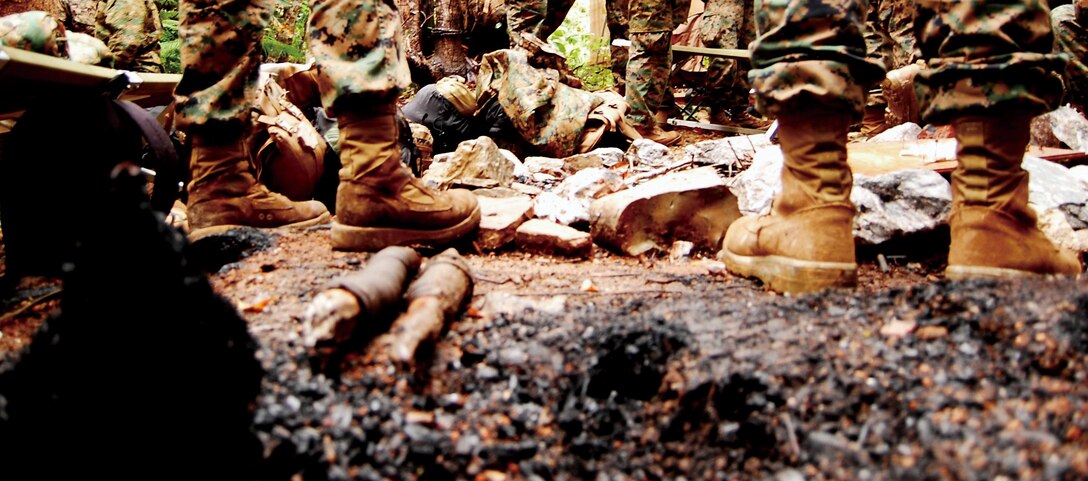 Marines gather around a fire pit at the Jungle Warfare Training Center, Camp Gonsalves, to discuss the day’s training exercise. The center is located in the rugged terrain of northern Okinawa and offers courses on jungle survival.