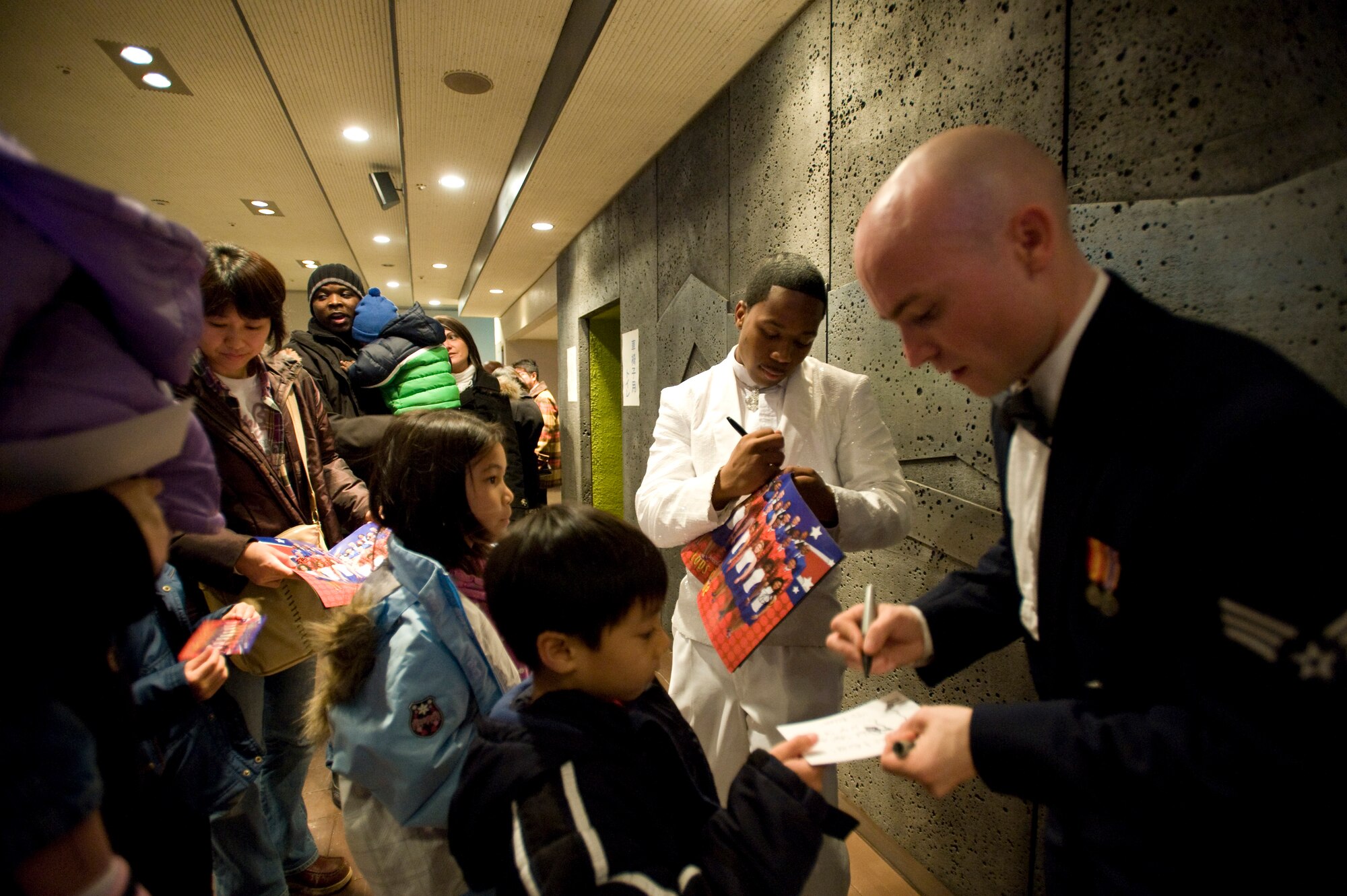 MISAWA CITY, Japan -- Senior Airmen Anthoney Williams, Tops in Blue trumpeter, and Jeffre Collins, Tops in Blue vocalist, sign autographs in the lobby of the Misawa Civic Center following their performance Dec. 27. Tops in Blue traveled to Yokota Air Base, Japan, for their next performance. (U.S. Air Force photo/Staff Sgt. Samuel Morse)