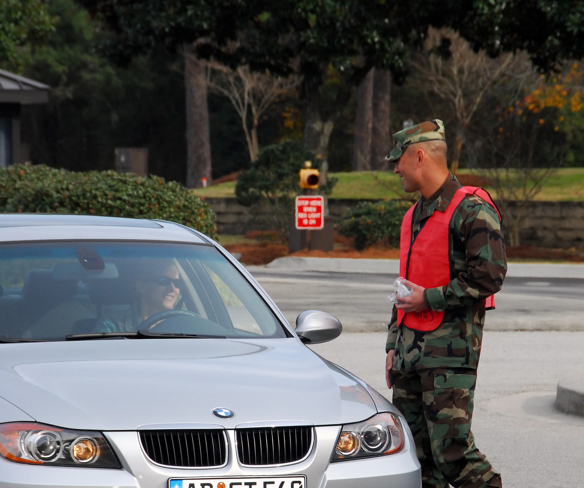 Maj. Gino Sarcomo greets a driver exiting Charleston AFB through the Dorchester Road main gate Dec. 23 during a holiday safety send-off. A total of 24 base agencies participated in the event, volunteering to man the Dorchester Road gate, the Rivers Avenue gate and the Gaylor Dining Facility for the safety sendoff to remind members of Team Charleston to put programs such as 0-0-1-3 into practice to while enjoying holiday festivities. Major Sarcomo is the 437th Communications Squadron commander. (U.S. Air Force photo/Staff Sgt. Daniel Bowles)
