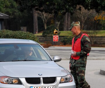 Maj. Gino Sarcomo greets a driver exiting Charleston AFB through the Dorchester Road main gate Dec. 23 during a holiday safety send-off. A total of 24 base agencies participated in the event, volunteering to man the Dorchester Road gate, the Rivers Avenue gate and the Gaylor Dining Facility for the safety sendoff to remind members of Team Charleston to put programs such as 0-0-1-3 into practice to while enjoying holiday festivities. Major Sarcomo is the 437th Communications Squadron commander. (U.S. Air Force photo/Staff Sgt. Daniel Bowles)
