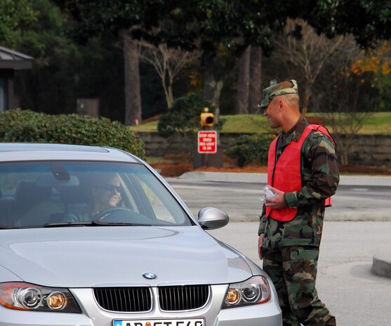 Maj. Gino Sarcomo greets a driver exiting Charleston AFB through the Dorchester Road main gate Dec. 23 during a holiday safety send-off. A total of 24 base agencies participated in the event, volunteering to man the Dorchester Road gate, the Rivers Avenue gate and the Gaylor Dining Facility for the safety sendoff to remind members of Team Charleston to put programs such as 0-0-1-3 into practice to while enjoying holiday festivities. Major Sarcomo is the 437th Communications Squadron commander. (U.S. Air Force photo/Staff Sgt. Daniel Bowles)
