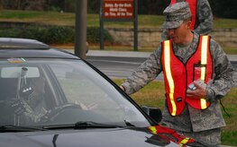 Maj. James Blackman hands a holiday safety flashlight to a driver leaving Charleston AFB through the Dorchester Road main gate Dec. 23. Major Blackman was joined by volunteers from the 437th Communications Squadron, 437th Medical Group, 437th Maintenance Group and 437th Airlift Wing staff during the safety send-off event which delivered more than 1,700 flashlights to drivers as a safety reminder during the holidays. Major Blackman is the 437th Maintenance Operations Squadron commander. (U.S. Air Force photo/Staff Sgt. Daniel Bowles)