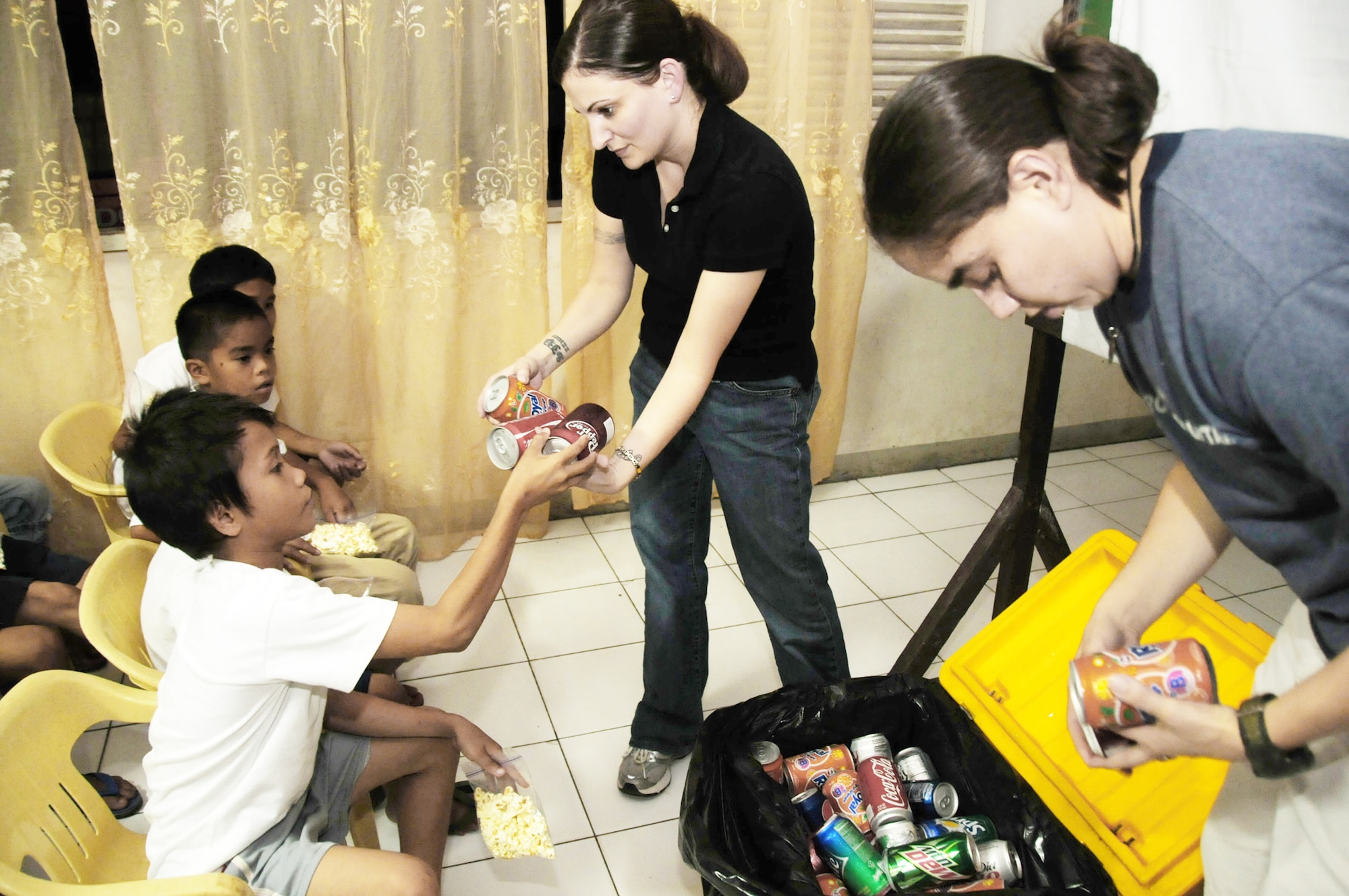Tech. Sgt. Amber Pacheco (left) and Petty Officer 2nd Class Nilsa Elizondo, both assigned to Joint Special Operations Task Force-Philippines, hand out sodas Dec. 23, 2009, during  movie night at the Social Development Center in Zamboanga, Philippines. JSOTF-P members regularly volunteer at the center, which houses abused, neglected or abandoned children. Task force members were at the center handing out holiday stockings and donated linen and curtains for the bedrooms. (U.S. Navy photo/Lt.j.g. Theresa Donnelly)