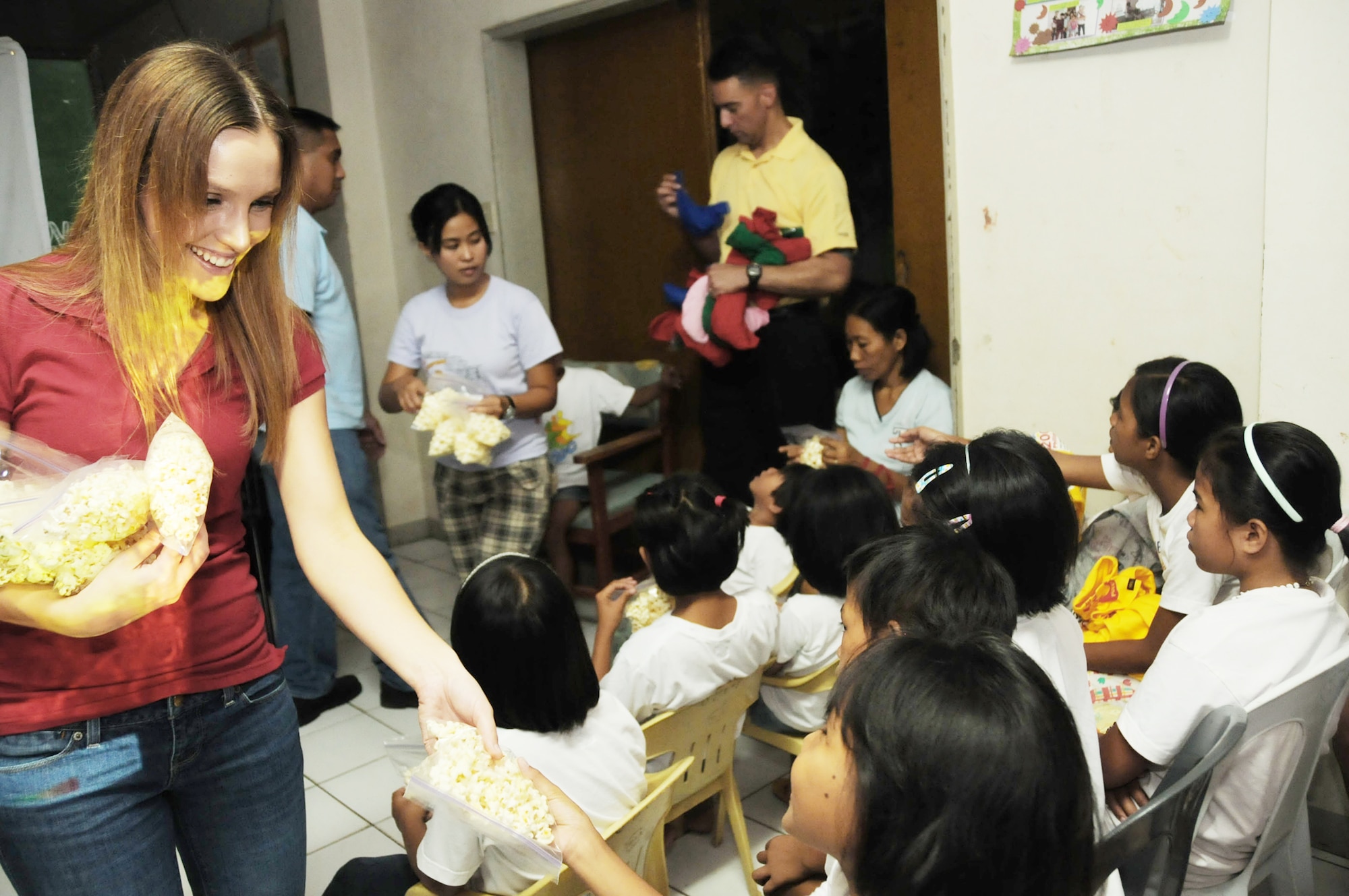 Staff Sgt. Jessica Brown, assigned to Joint Special Operations Task Force-Philippines, hands out popcorn Dec. 23, 2009, during movie night at the Social Development Center in Zamboanga, Philippines. JSOTF-P members regularly volunteer at the center, which houses abused, neglected or abandoned children. Task force members were at the center handing out holiday stockings and donated linen and curtains for the bedrooms. (U.S. Navy photo/Lt.j.g. Theresa Donnelly)
