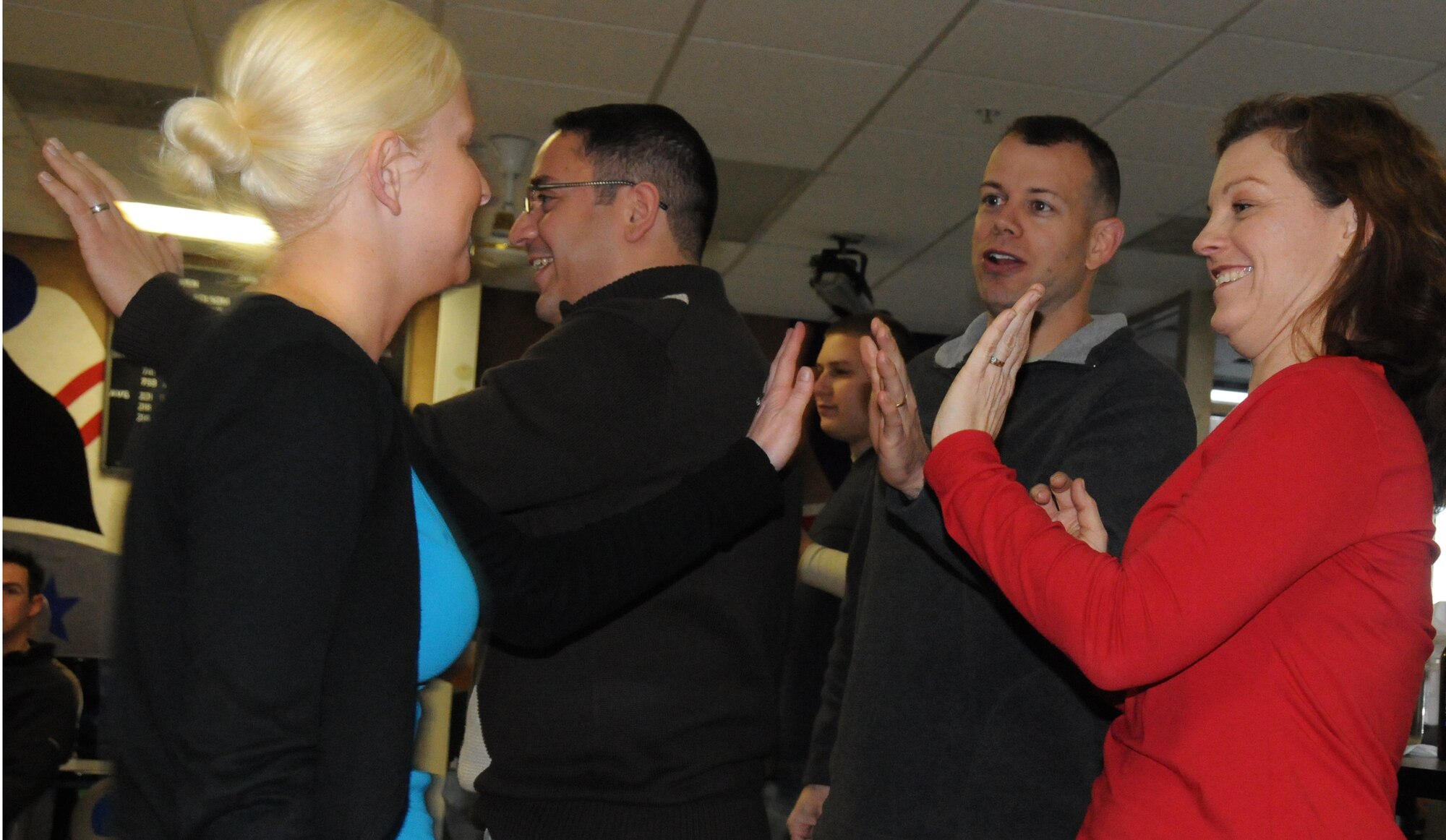 Master Sgt. Craig Burton and Master Sgt. Tammy Coffman give Senior Airman Jamie Feldhacker a high-five for bowling a good round. Staff Sgt. Adrian Walker high fives another teammate at the 442nd Fighter Wing Christmas party during the December unit training assembly. (U.S. Air Force photo/Staff Sgt. Tom Talbert)