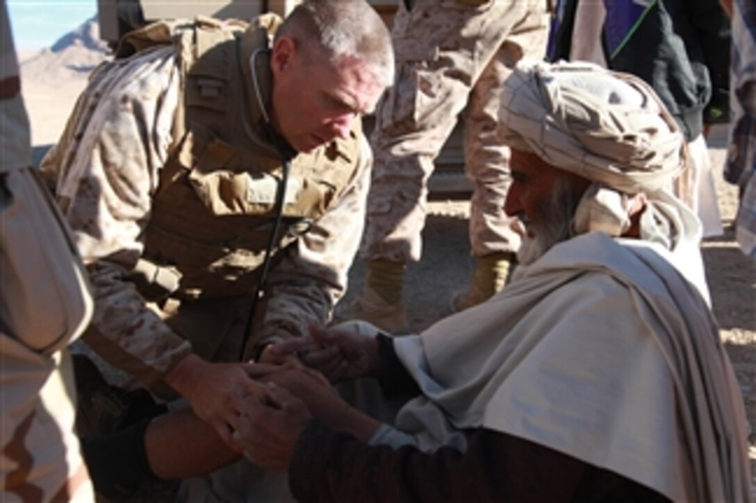 U.S. Navy Lt. Cmdr. Bill Schalck, with 3rd Battalion, 4th Marine Regiment, examines an Afghan man's knee during a combined medical engagement in Now Zad, Afghanistan, on Dec. 18, 2009.  Schalck and the other medics provide medical care for anyone who comes to the engagement.  