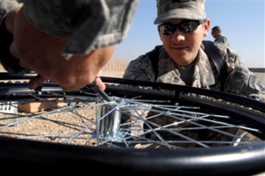 U.S. Army Pfc. Shane Dunningham supervises as a wheel is fixed on a wheelchair Dec. 15, 2009, at Forward Operating Base Delta, Iraq. The wheelchairs were later distributed to the local Children's Hospital in Al Kut. Dunningham is assigned to the 3rd Infantry Division's 1st Battalion, 10th Field Artillery, 3rd Heavy Brigade Combat Team.