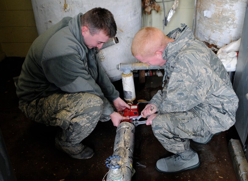 Staff Sgt. Brian Noble (left) and Senior Airman Jonathan Jones replace a water circulation pump outside the base laundry room facility at Osan Air Base, Republic of Korea Dec. 29. Both Airmen are heating ventilation and air conditioning technicians. ( U.S. Air Force photo/ Senior Airman Stephenie Wade) 
