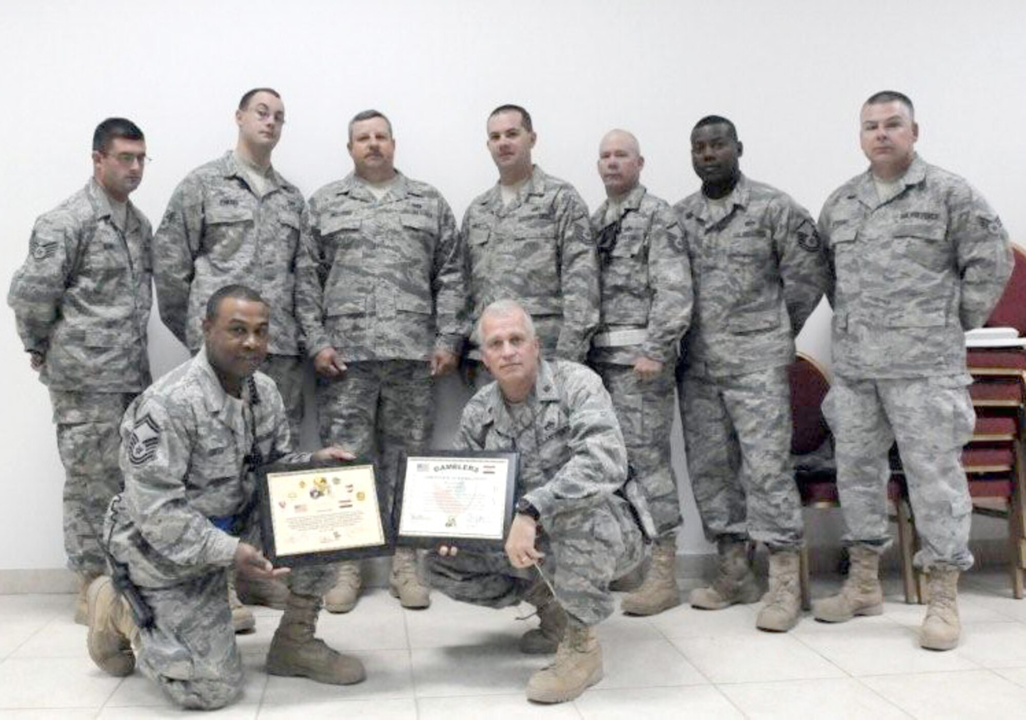 Senior Master Sgt. Jeffrey Smith (front left), holds a certificate awarded to members of the 506th Expeditionary Civil Engineer Squadron, Kirkuk Regional Air Base, Iraq. Beside him, also holding a certificate, is the 506th ECES Commander Maj. David Walker. The U.S. Army recognized the CE team for crane and forklift support as well as their assistance in transporting modular trailers. Sergeant Smith and Master Sgt. Antonio Bray (back row, second from right) are 512th Civil Engineer Squadron members currently deployed to Kirkuk RAB.  