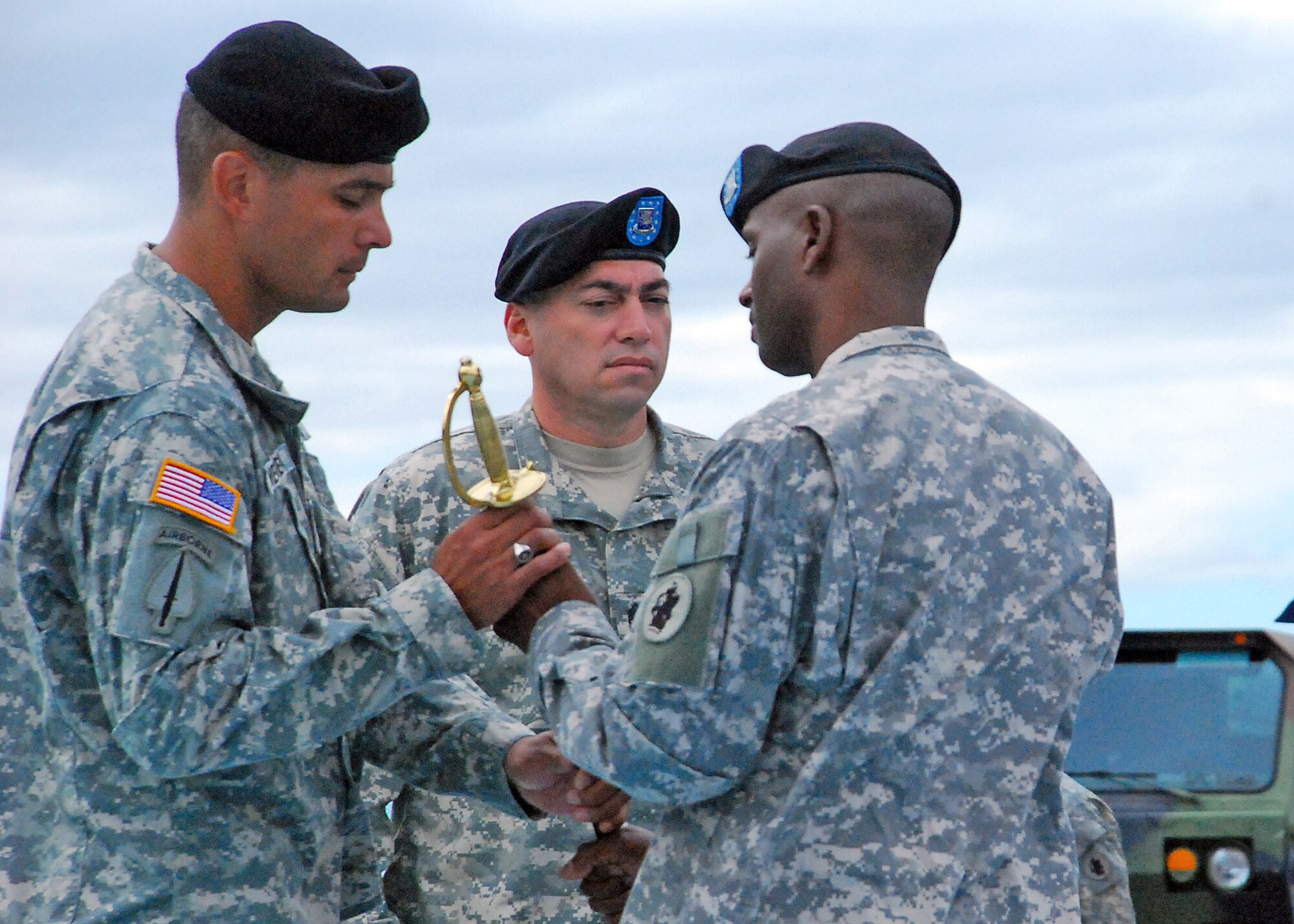 Outgoing 1st Battalion, 228th Aviation Regiment Command Sgt. Maj. Carlos Escalera passes the Non-commissioned Officer Sword to Lt. Col. Salome Herrera, 1/228th commander during a change of responsibility ceremony Dec. 29 here. The NCO Sword was then passed to Command Sgt. Maj. Lucio DeAnda as he assumes responsibilities as the 1/228th command sergeant major. (Photo by U.S. Air Force Staff Sgt. Bryan Franks)