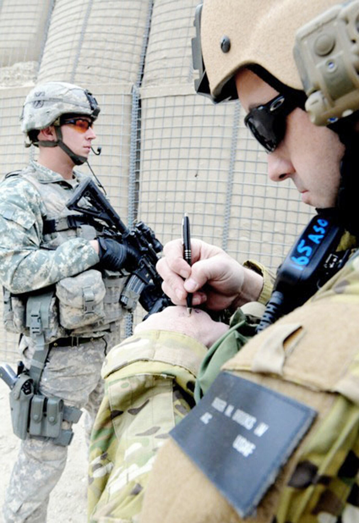 Capt. Roger M. Brooks IV takes coordinates at an Afghan border police observation post in the mountains of Achin district in eastern Afghanistan's Nangarhar province, Dec. 20, 2009, as a tower guard provides over watch. Captain Brooks is the commander of a 12-man joint terminal attack controller team in Afghanistan. (U.S. Army photo/Sgt. Tracy J. Smith)