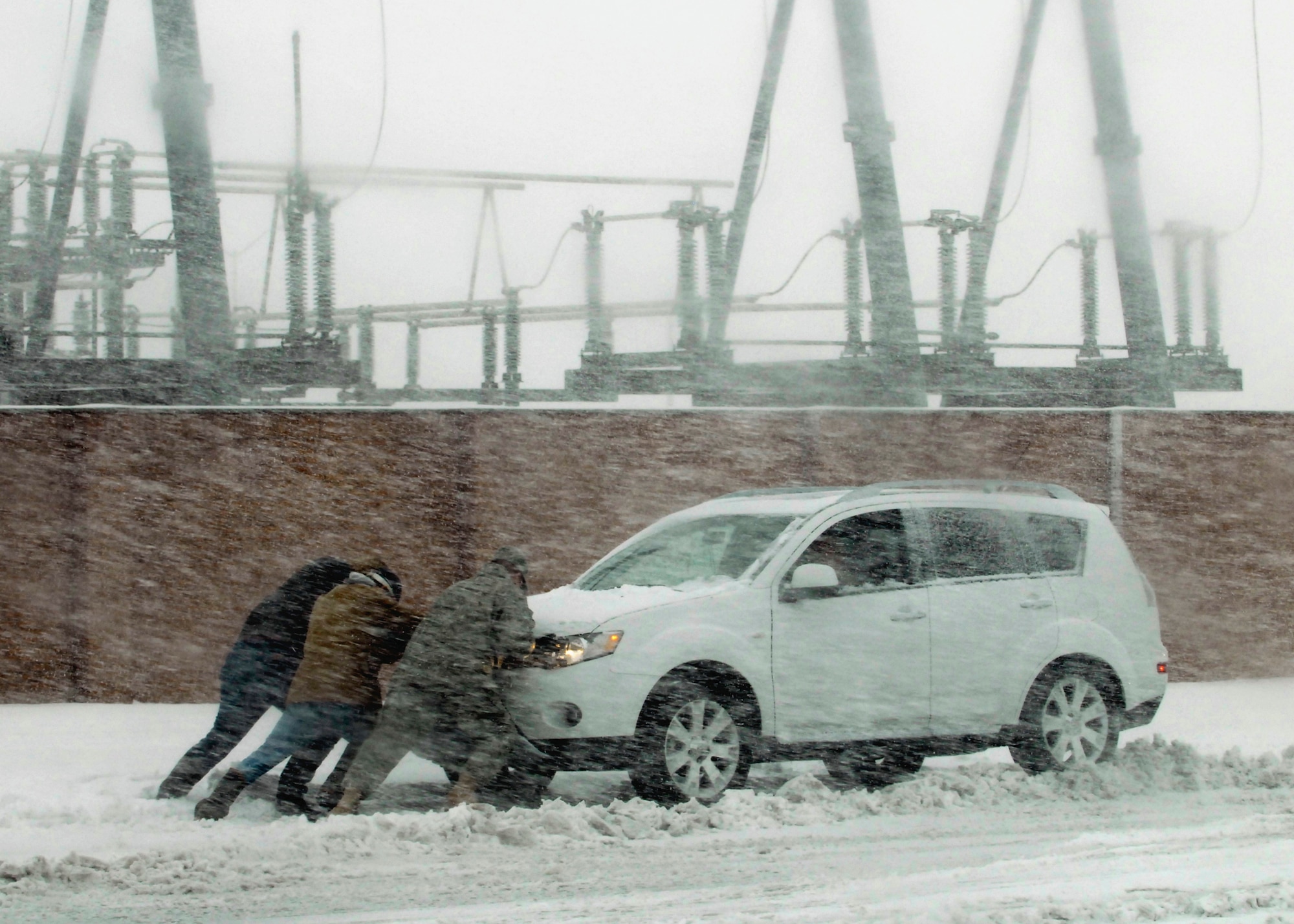 A motorist on Sheppard Air Force Base, Texas, gets three pairs of helping hands Dec. 24 as a blizzard rips through North Texas, dumping between 10-15 inches of snow and ice. (U.S. Air Force photo/Harry Tonemah)