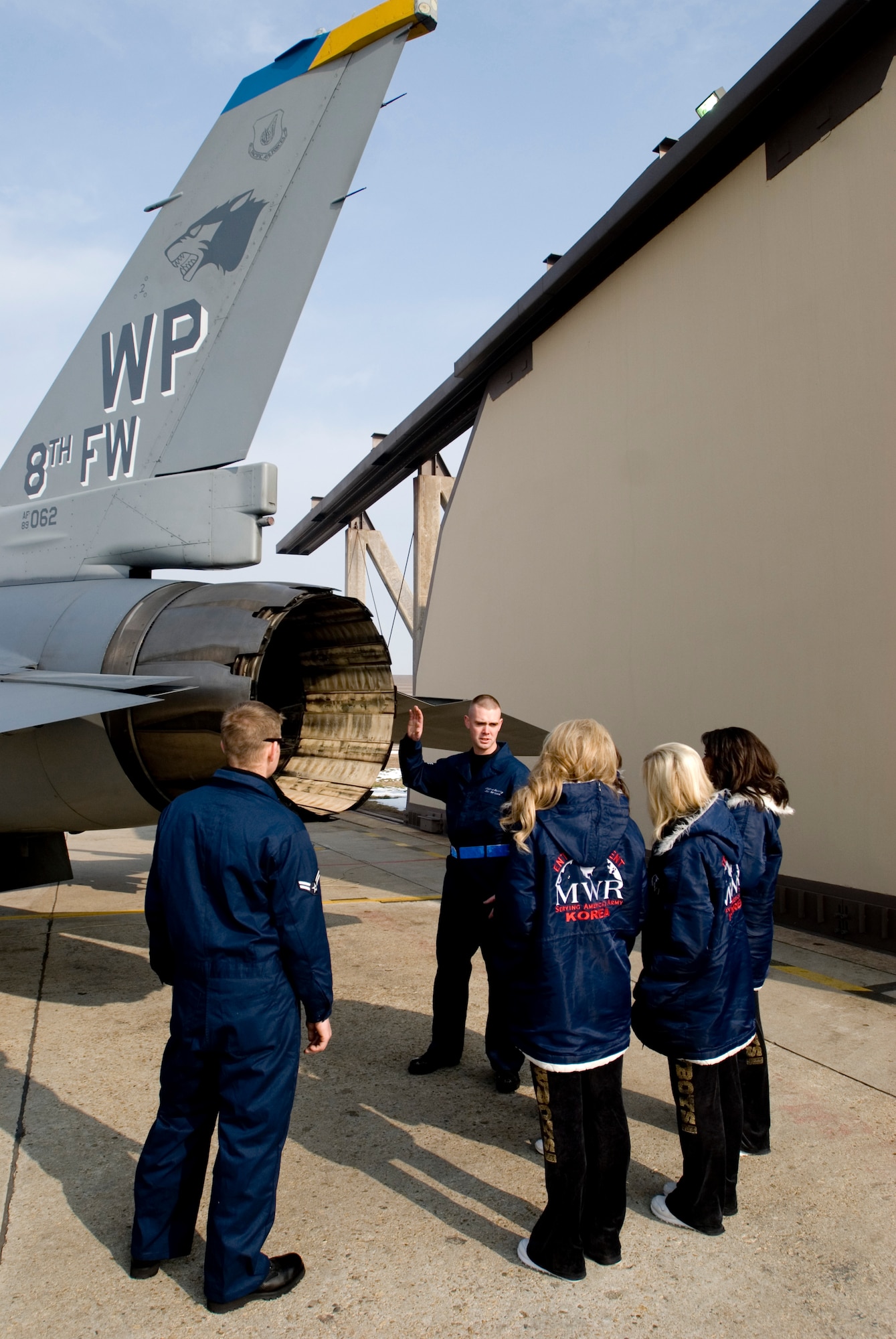 KUNSAN AIR BASE, Republic of Korea -- SSgt Matthew Rettig and Airman 1st Class Ronald Nielsen, 8th Aircraft Maintenance Squadron,  describe F-16 Fighting Falcon engine specifications to the Dallas Cowboys Cheerleaders Dec. 24. The cheerleaders later signed autographs and performed a 90-minute show for Wolf Pack Airmen. (U.S. Air Force photo/Senior Airman Jonathan Steffen) 