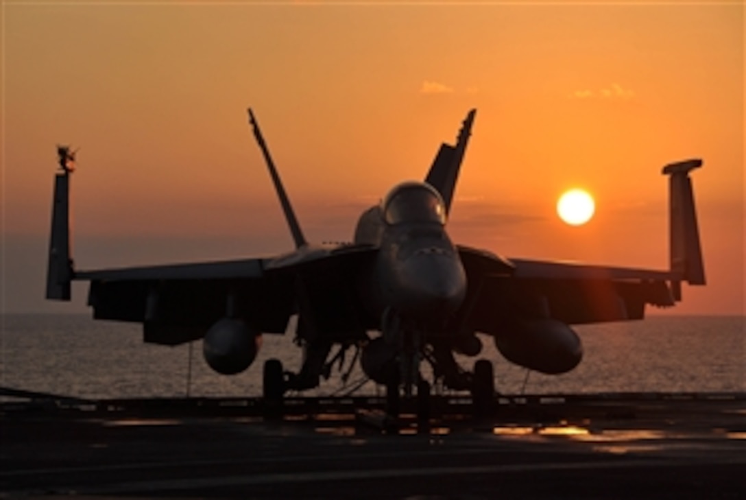 A U.S. Navy F/A-18E Super Hornet aircraft sits tied-down on the flight ...