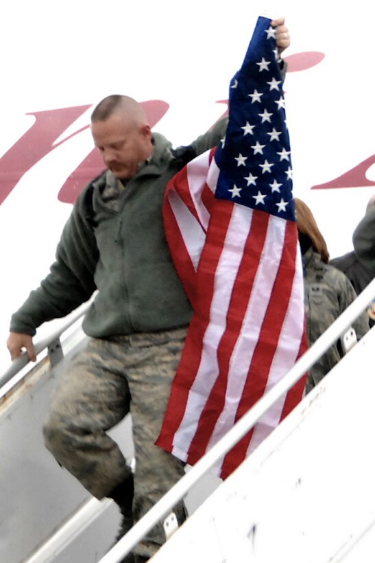 Master Sgt. Ted Davis, fulfilling a time honored tradition at the 132nd Fighter Wing, Des Moines, Iowa by carrying the American flag as he is the first to exit the aircraft of returning deplorers. Master Sgt Davis along with 270 members of the 132nd Fighter Wing returned December 24 to the Iowa Air National Guard Base located at the Des Moines International Airport, from Joint Base Balad, Iraq after filling an aviation package Aerospace Expeditionary Force rotation. (U.S. Air Force/Senior Master Sgt. Tim Day)(Released)