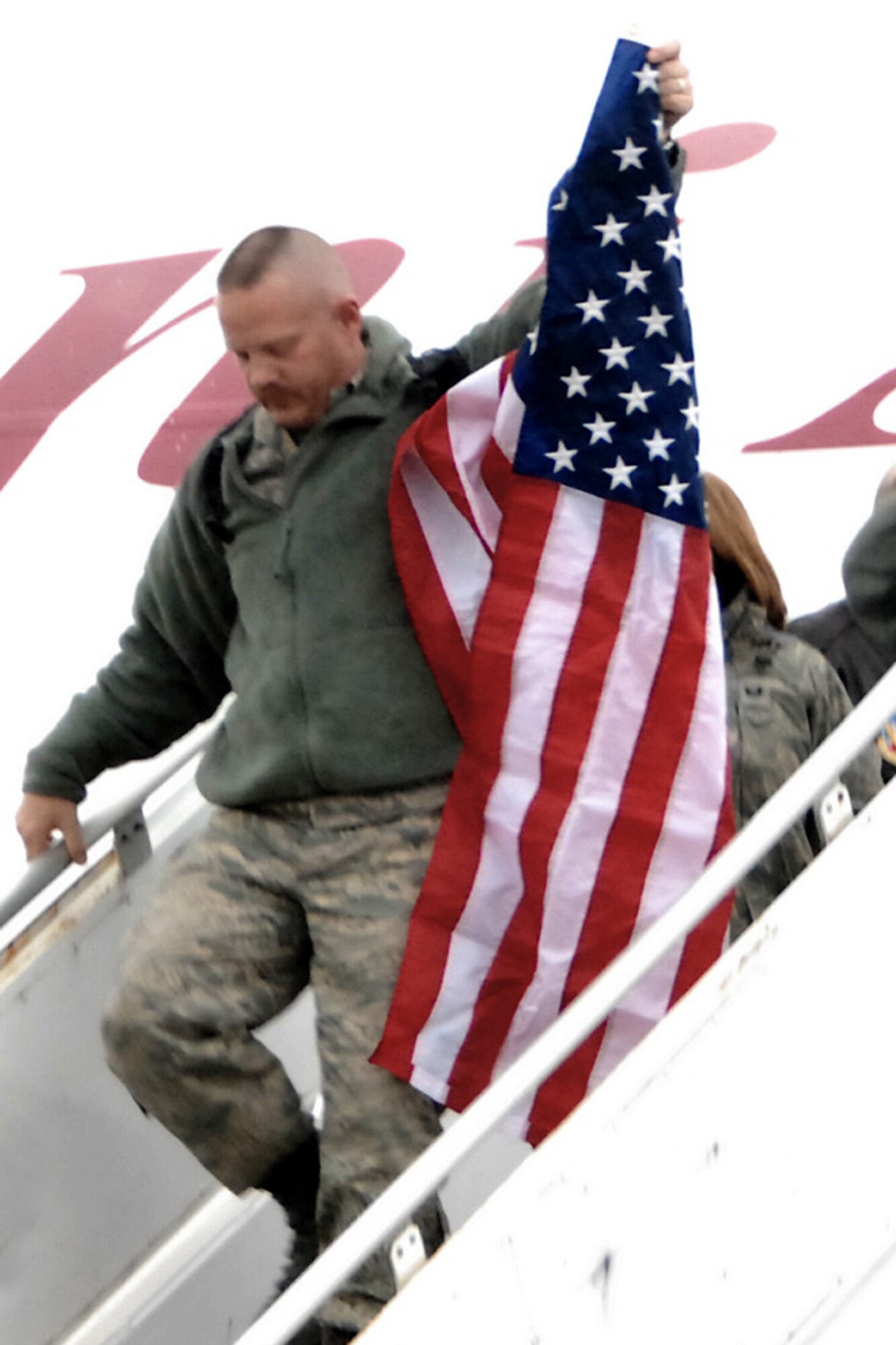 Master Sgt. Ted Davis, fulfilling a time honored tradition at the 132nd Fighter Wing, Des Moines, Iowa by carrying the American flag as he is the first to exit the aircraft of returning deplorers. Master Sgt Davis along with 270 members of the 132nd Fighter Wing returned December 24 to the Iowa Air National Guard Base located at the Des Moines International Airport, from Joint Base Balad, Iraq after filling an aviation package Aerospace Expeditionary Force rotation. (U.S. Air Force/Senior Master Sgt. Tim Day)(Released)