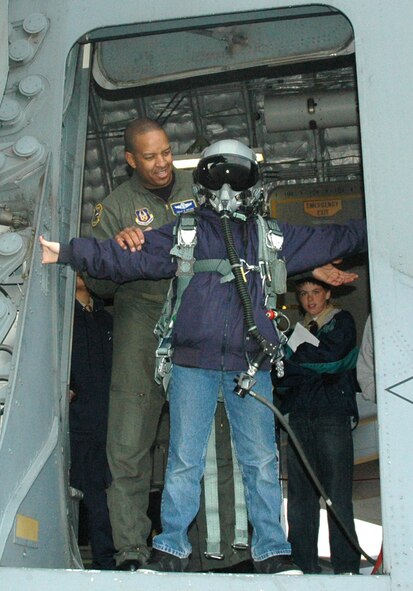 MCCHORD AIR FORCE BASE, Wash.- Senior Master Sgt. Derek Bryant, left, loadmaster with the 728th Airlift Squadron here, dons a Boy Scout in a parachute, helmet, and an oxygen mask on a C-17 Globemaster static display here in order to give the visiting Boy Scouts the experience of an airman getting ready to jump out of a C-17. Boy Scout troops 249 out of Richland, Wash. and 594, Maple Valley, Wash. were taken onto the aircraft so they could earn their Aviation Merit badges. (U.S. Air Force photo/Master Sgt. Jake Chappelle)