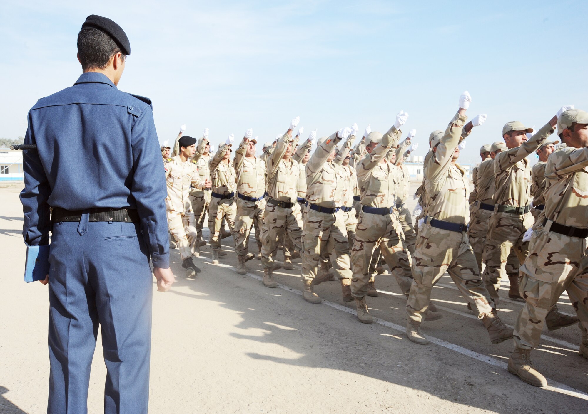 An Iraqi air force training instructor observes new recruits marching in a pass in review parade at their graduation ceremony from the basic military training Top Off course at the Iraqi Air Force Training School Dec. 28, 2009, at Camp Taji, Iraq. The staff incorporated discipline, marching, and drill during the morning sessions and academics in the afternoon. (U.S. Air Force photo/Master Sgt. Trish Bunting)
  